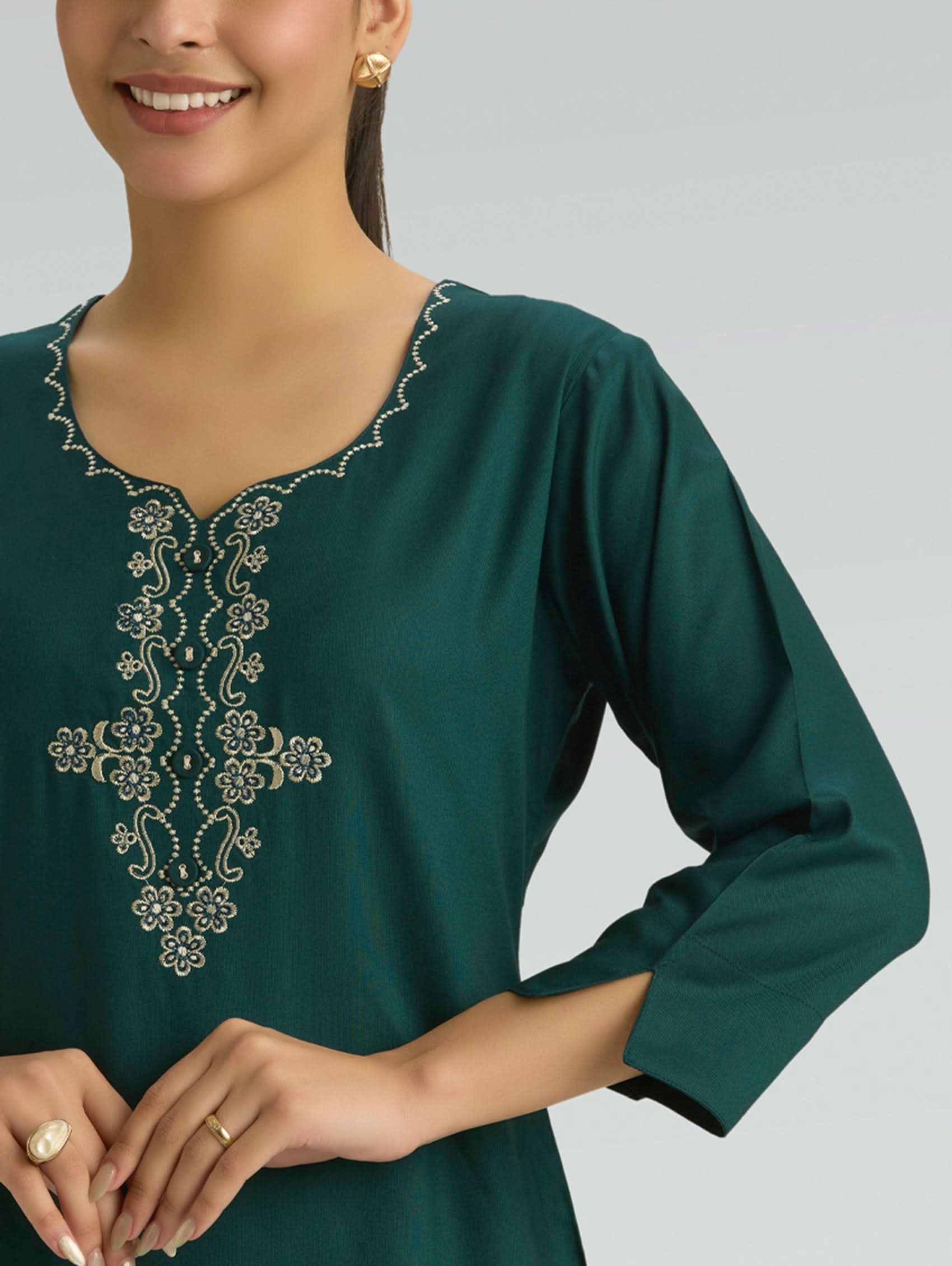 Green embroidered top worn by a person on a gray background
