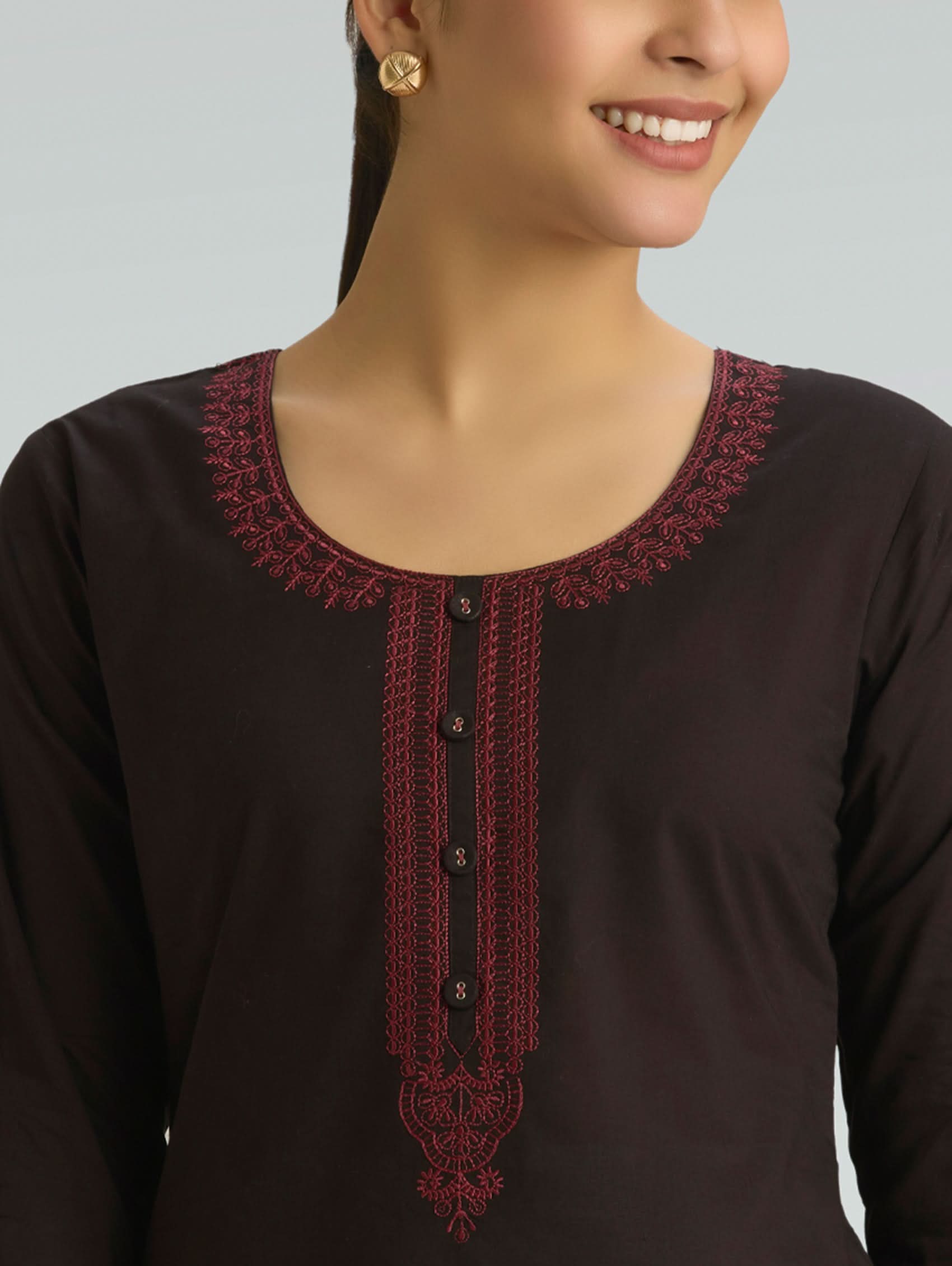 Black top with intricate red lace detailing on a plain background