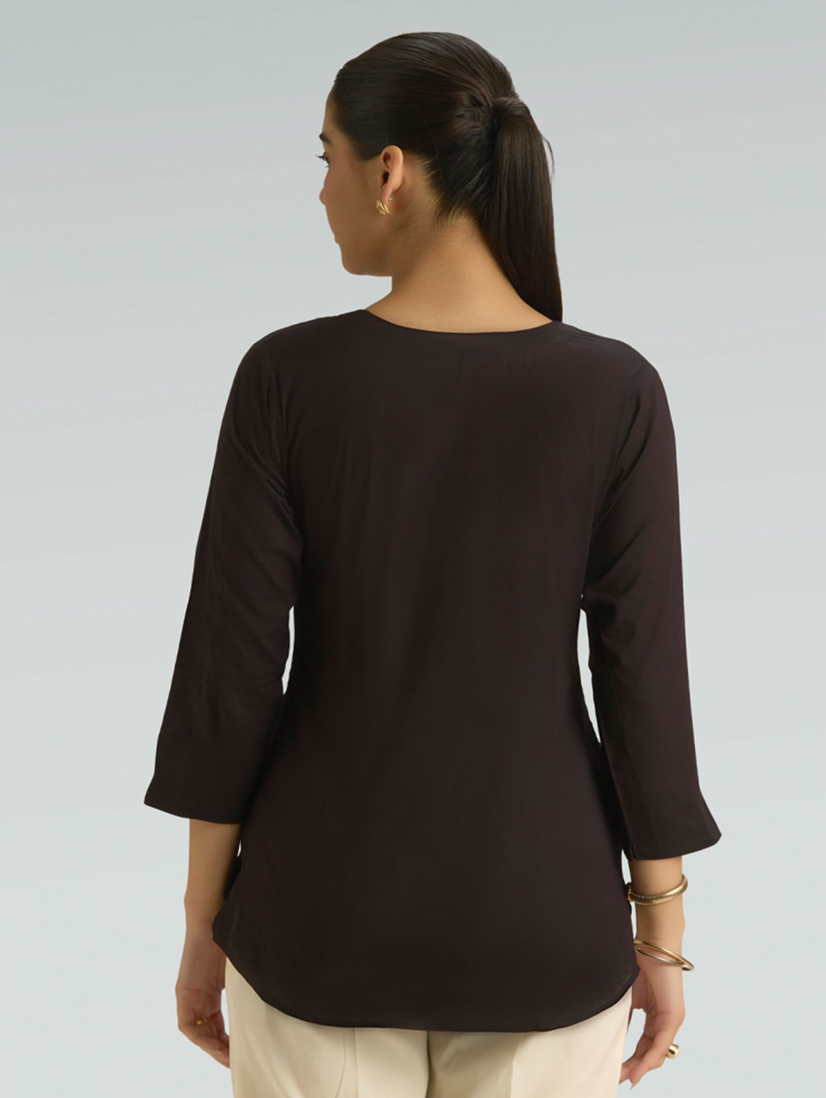 Woman wearing a brown long-sleeve top on a plain background