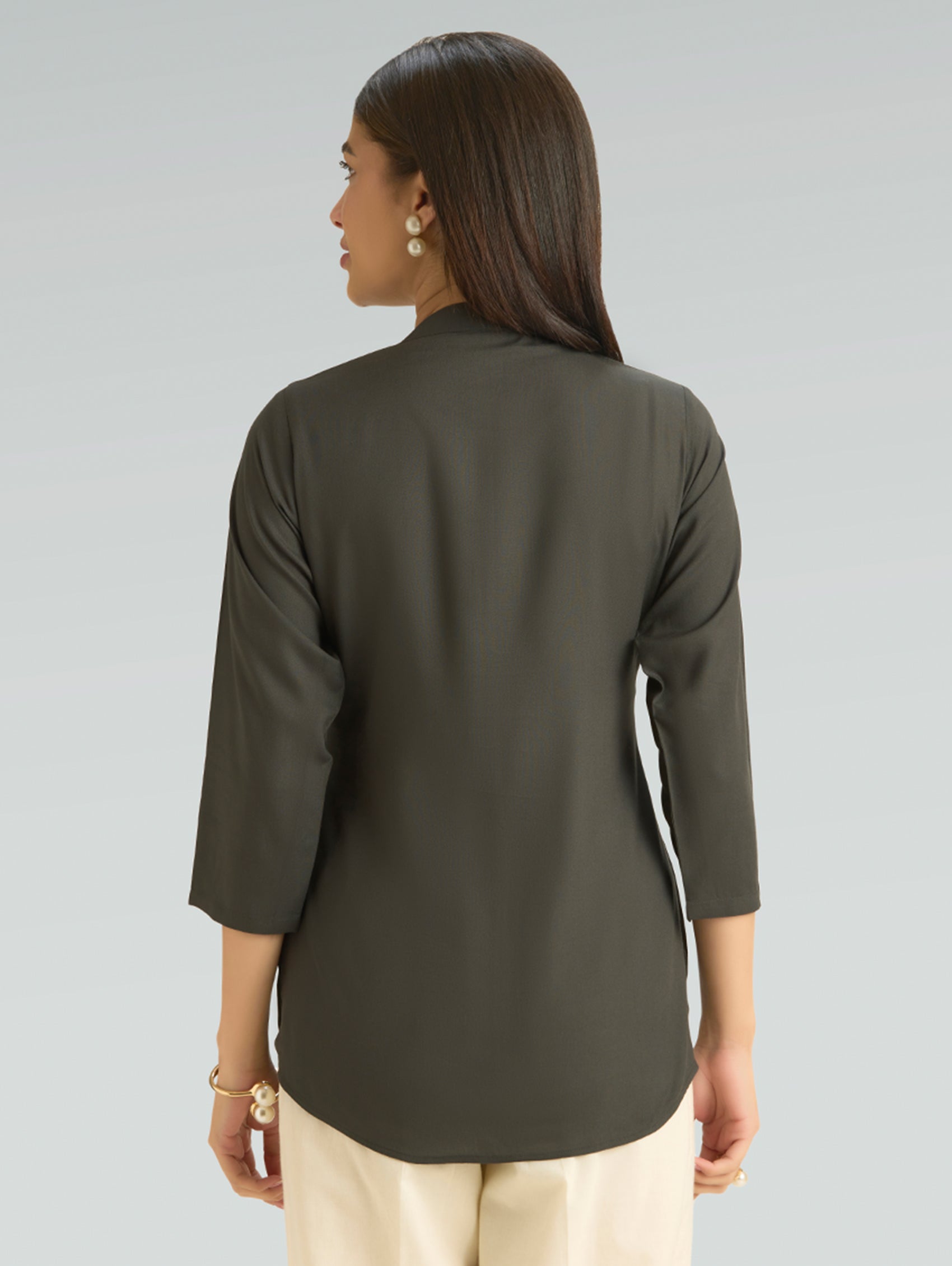 Woman wearing a green long-sleeve top on a gray background