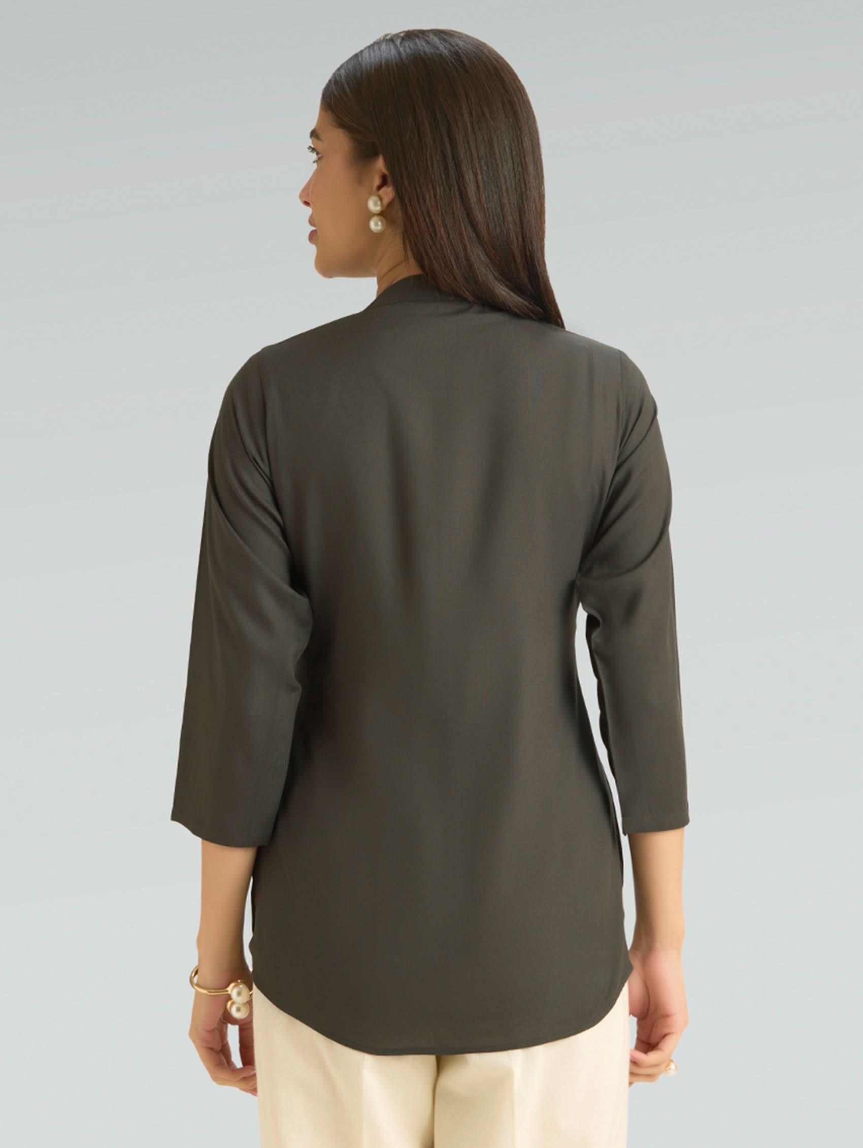 Woman wearing a green long-sleeve top on a gray background
