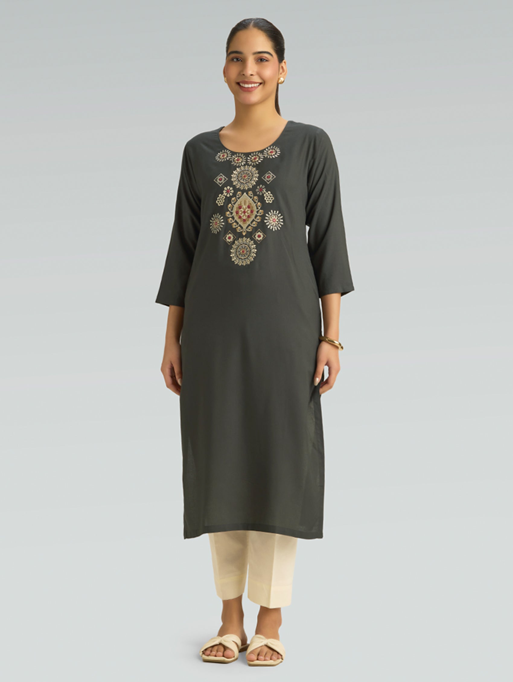 Woman wearing a dark green kurta with embroidery on a gray background