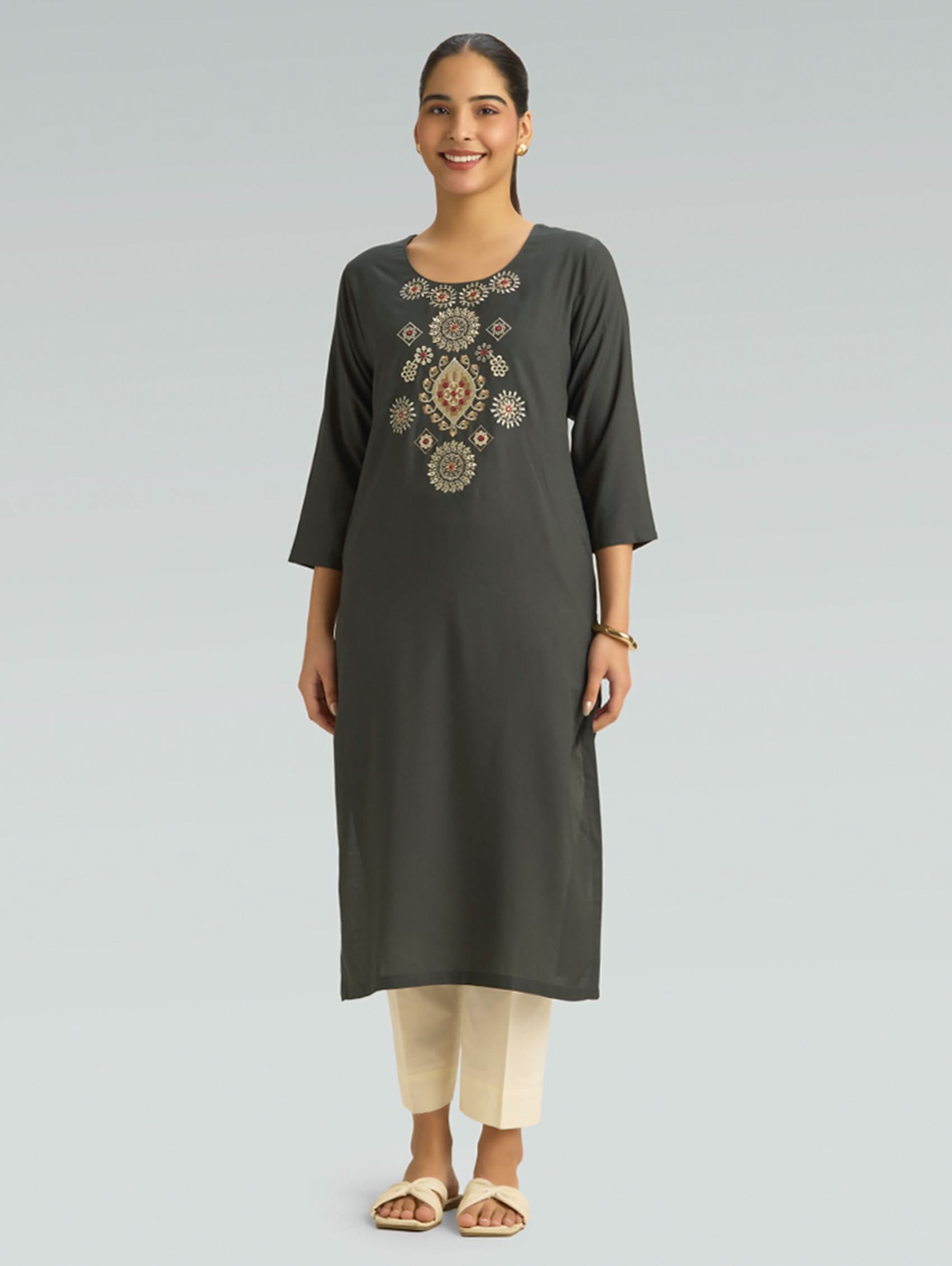 Woman wearing a dark green kurta with embroidery on a gray background