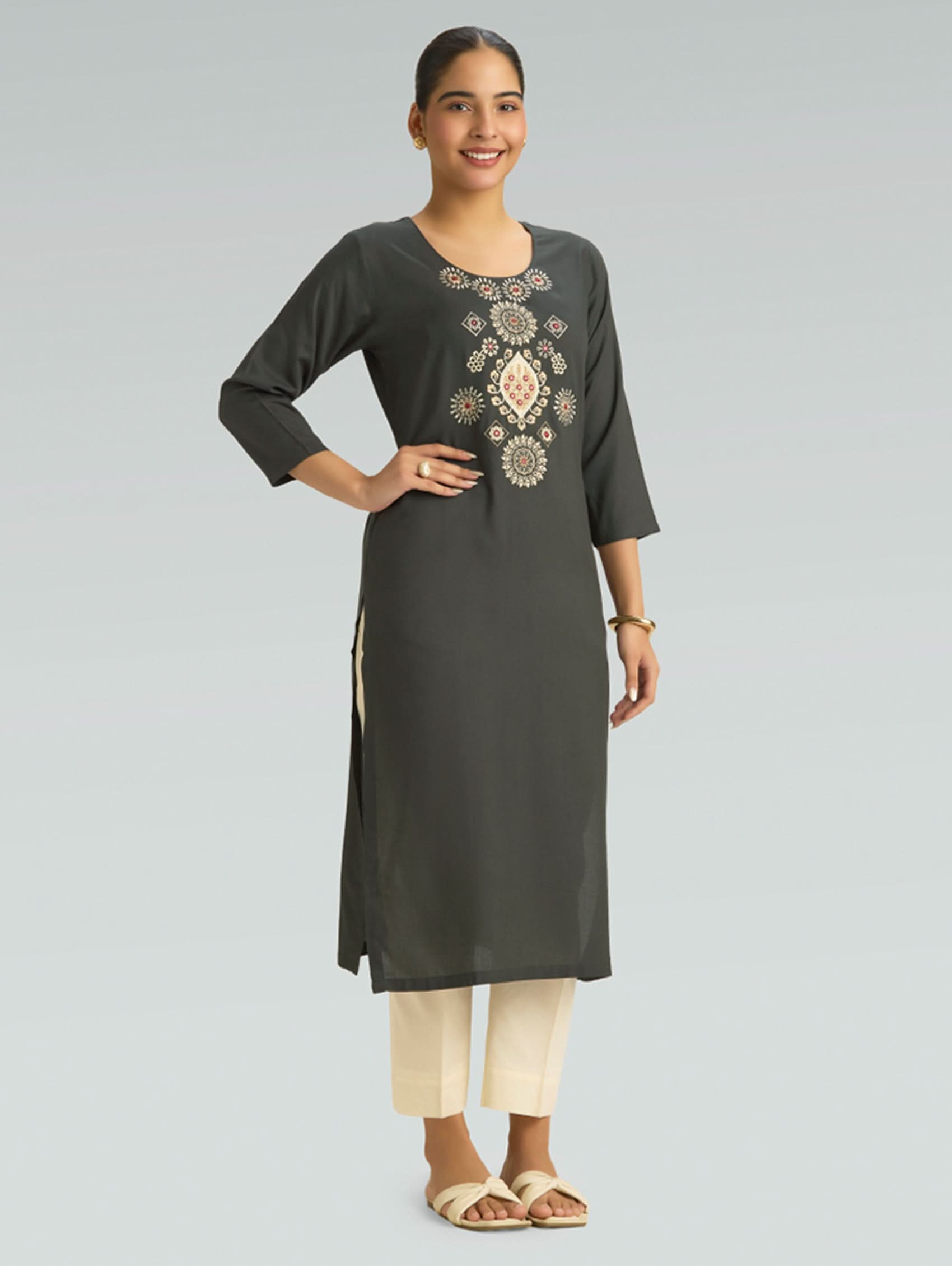Woman wearing a dark gray kurta with intricate embroidery on a light gray background
