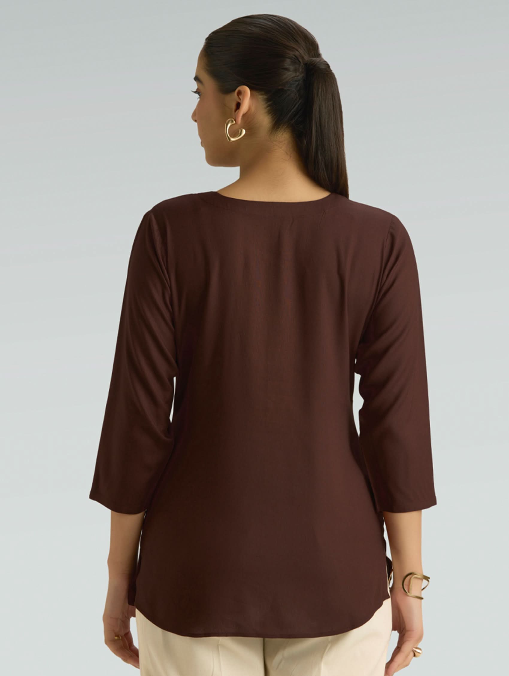 Woman wearing a brown long-sleeve top on a light gray background
