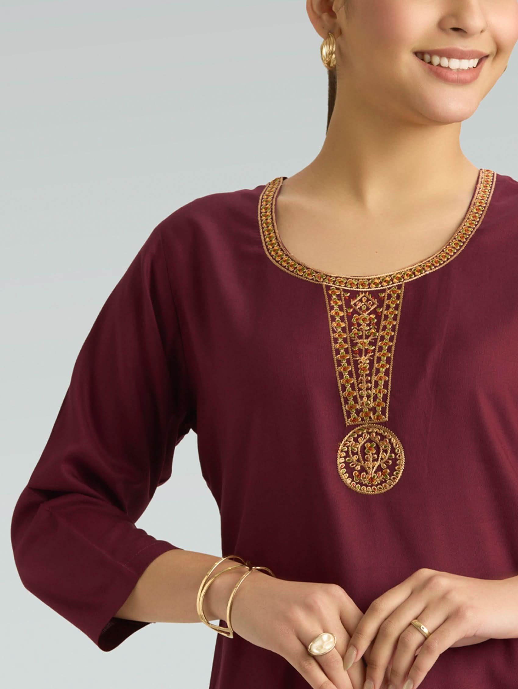 Maroon top with gold embroidery on a plain background