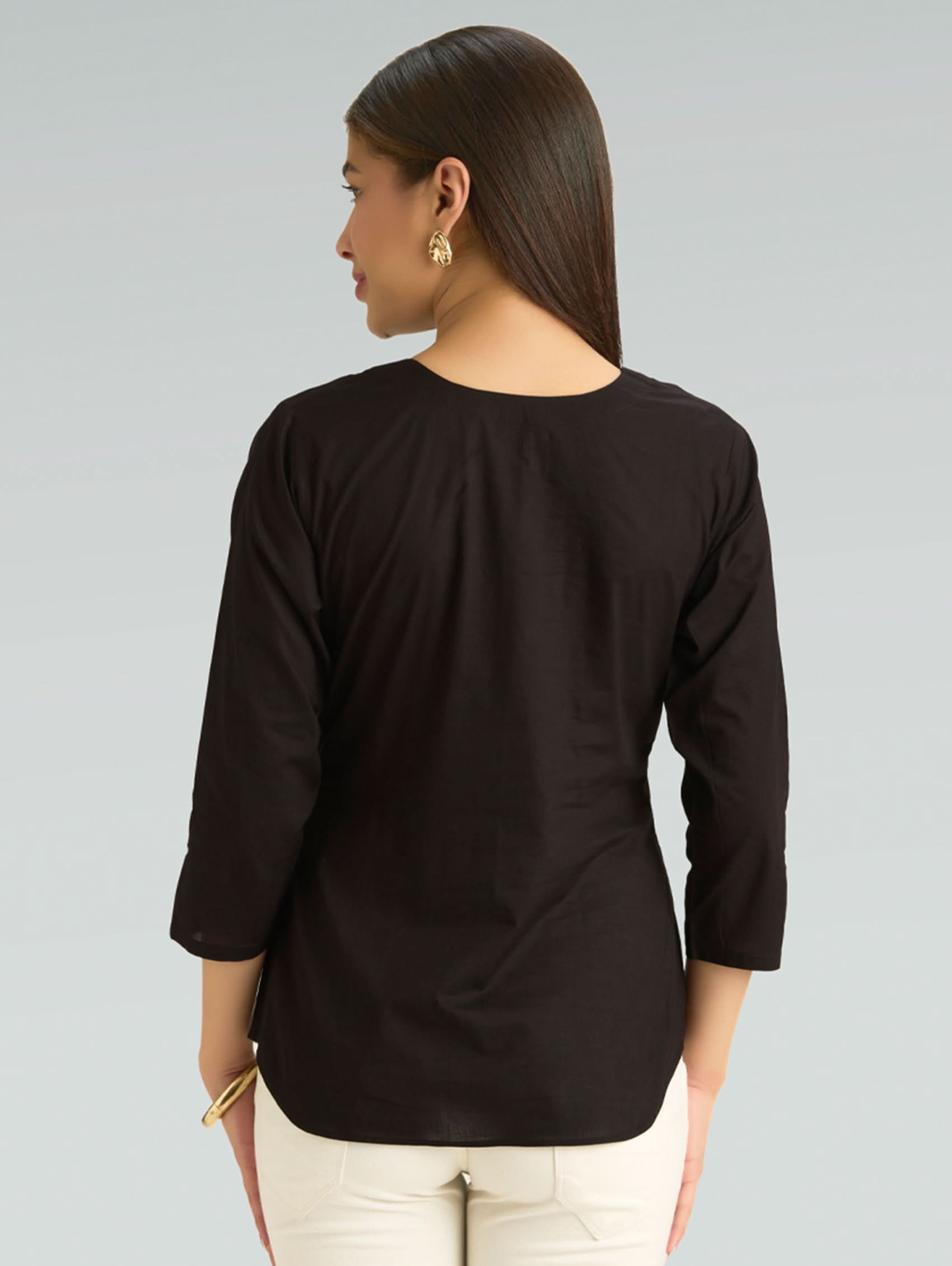 Woman wearing a black top with 3/4 sleeves on a gray background