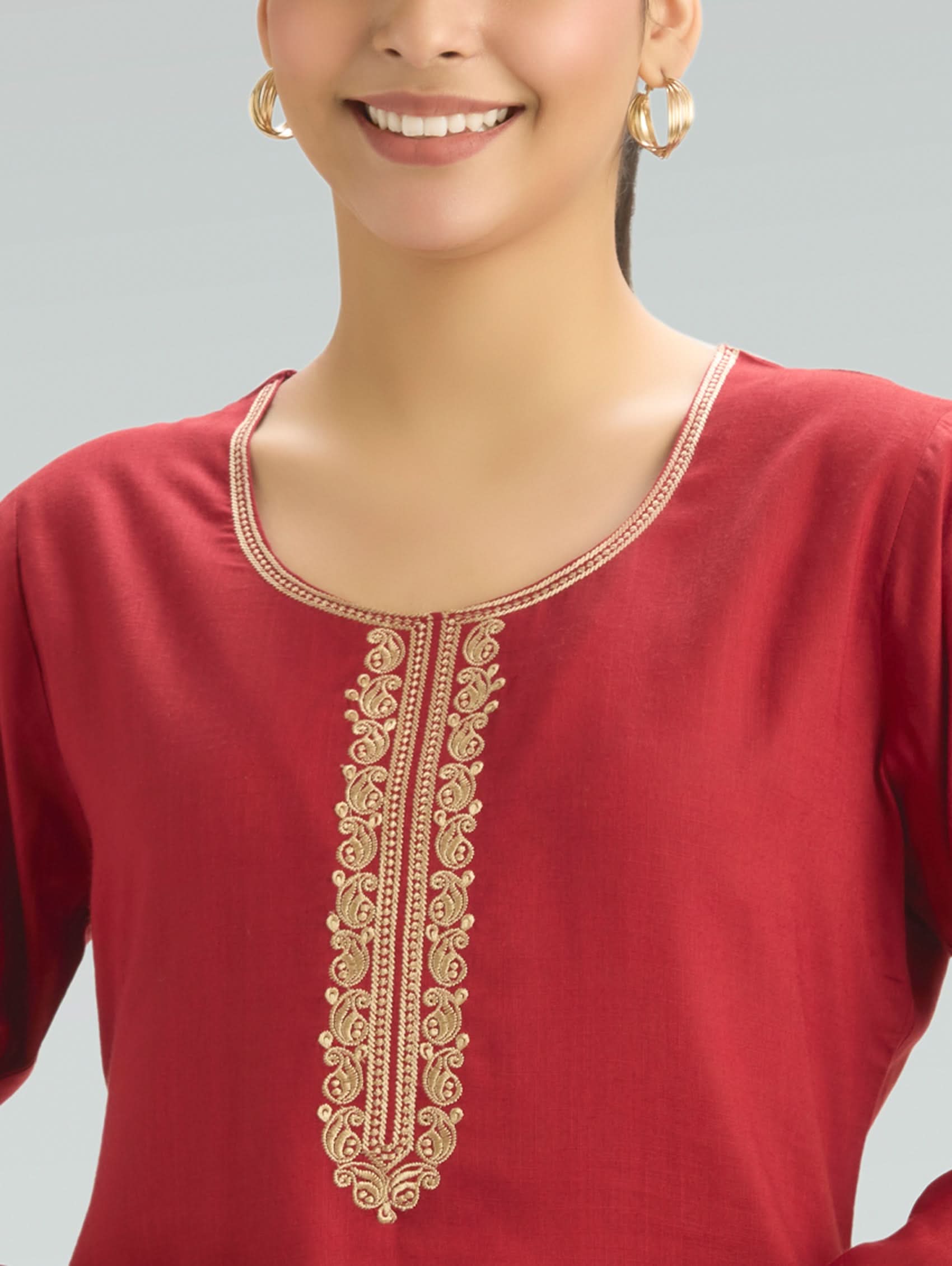 Red kurta with gold embroidery on a gray background