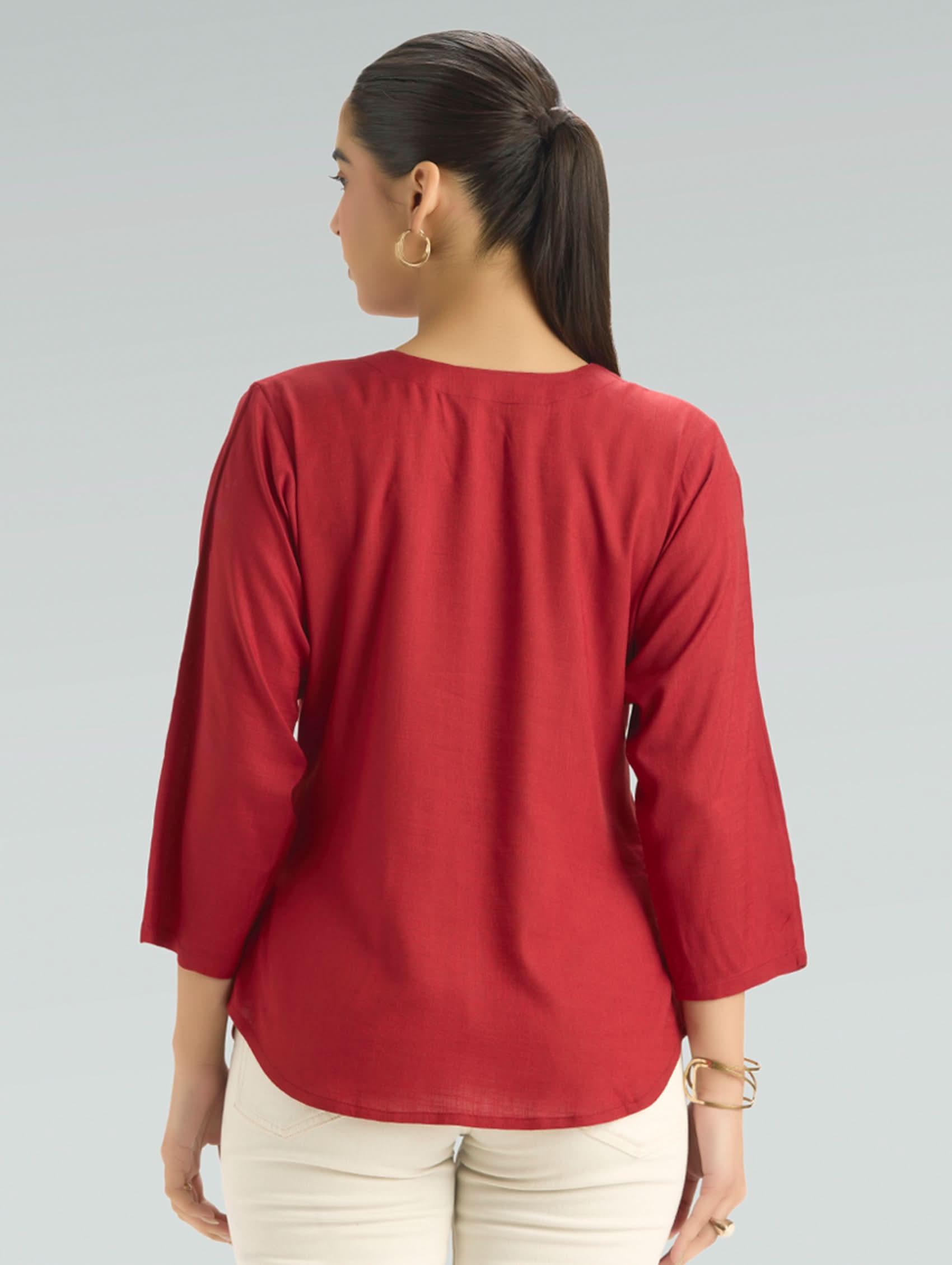 Woman wearing a red top with a plain background