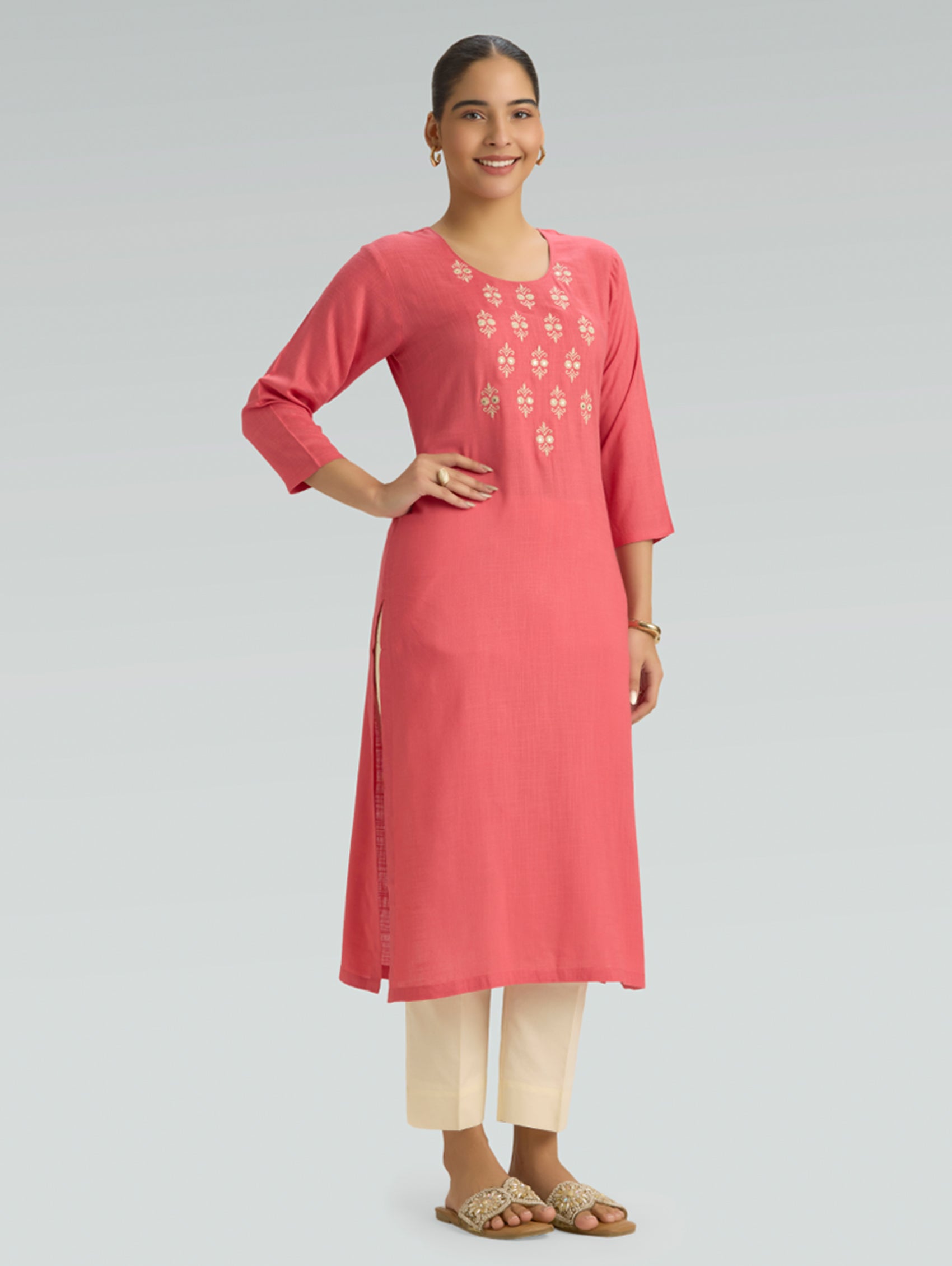 Woman wearing a pink kurta with embroidery on a gray background