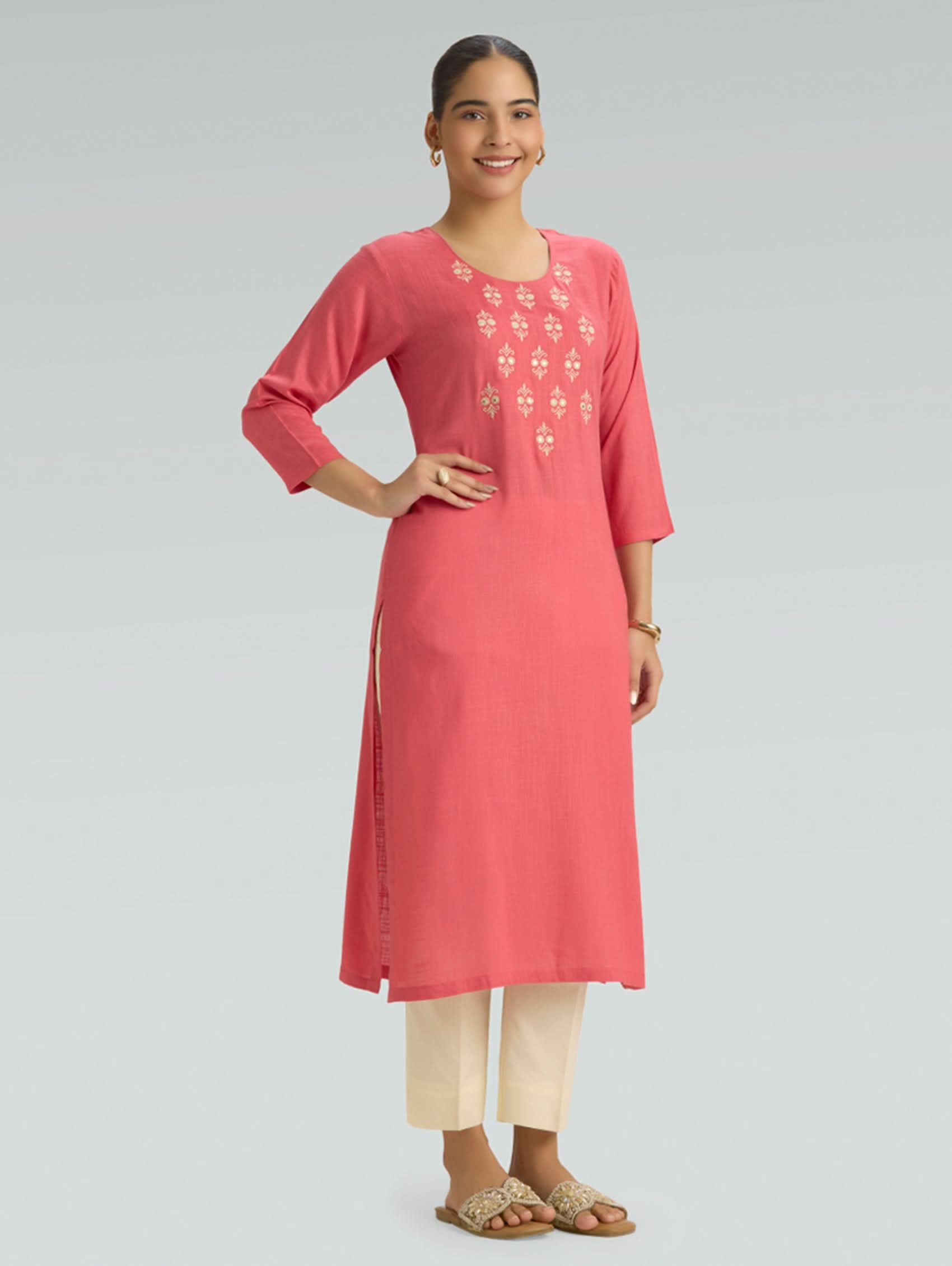 Woman wearing a pink kurta with embroidery on a gray background