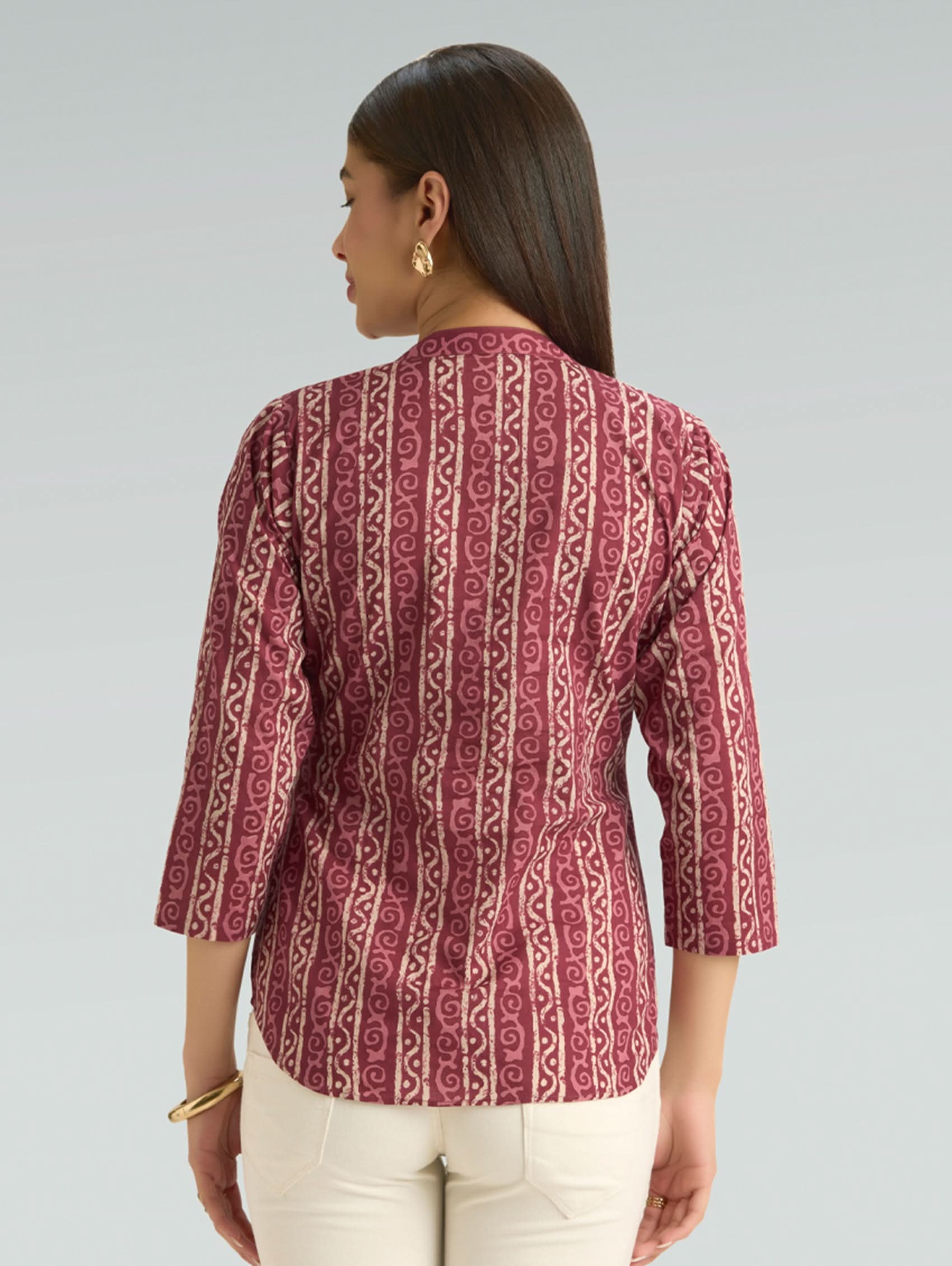 Woman wearing a red patterned blouse against a gray background