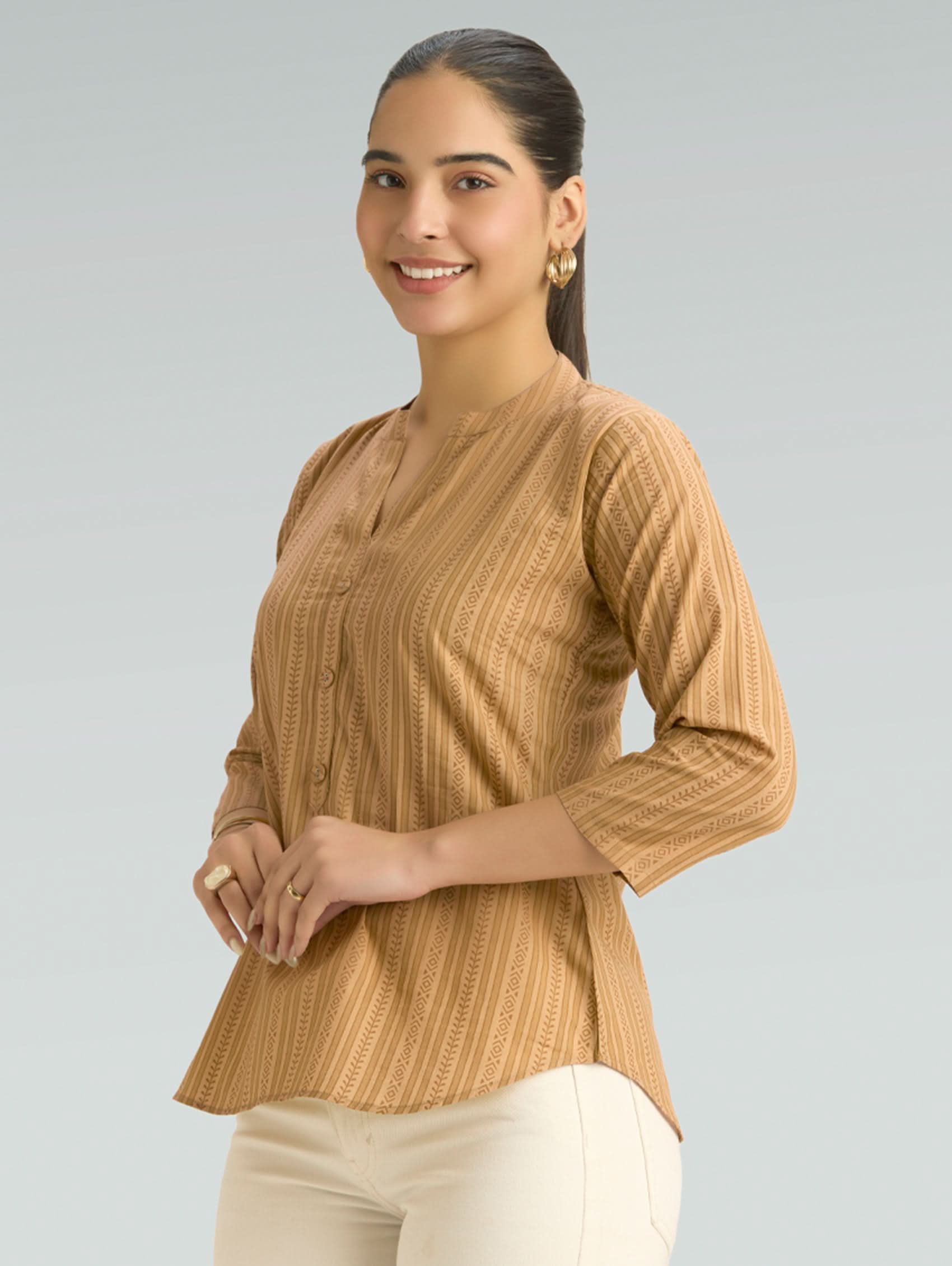 Woman wearing a brown textured top against a gray background