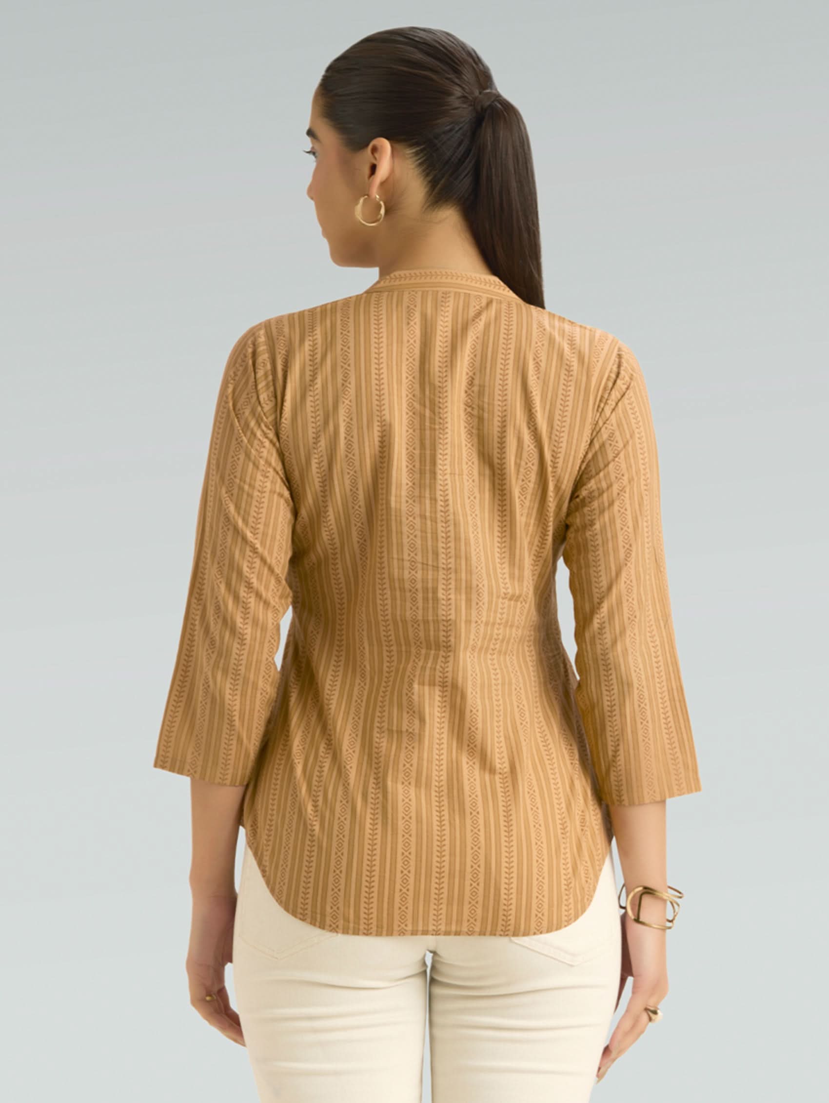 Woman wearing a brown striped shirt against a gray background