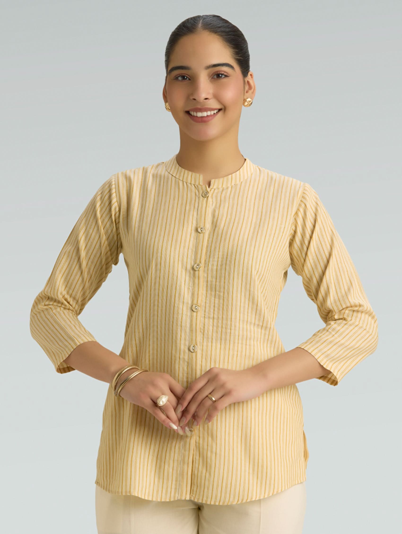 Woman wearing a yellow striped shirt against a gray background