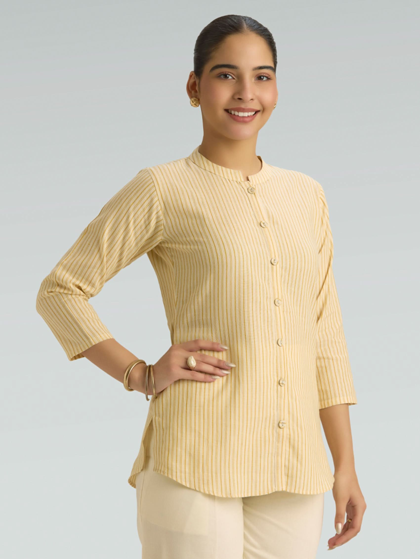 Woman wearing a light yellow ribbed blouse with a plain background