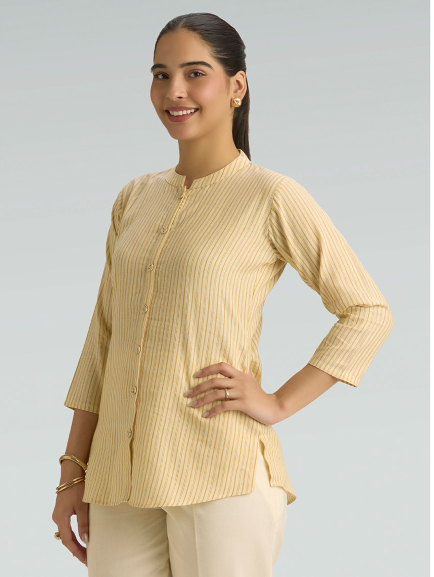 Woman wearing a beige striped shirt and pants on a gray background