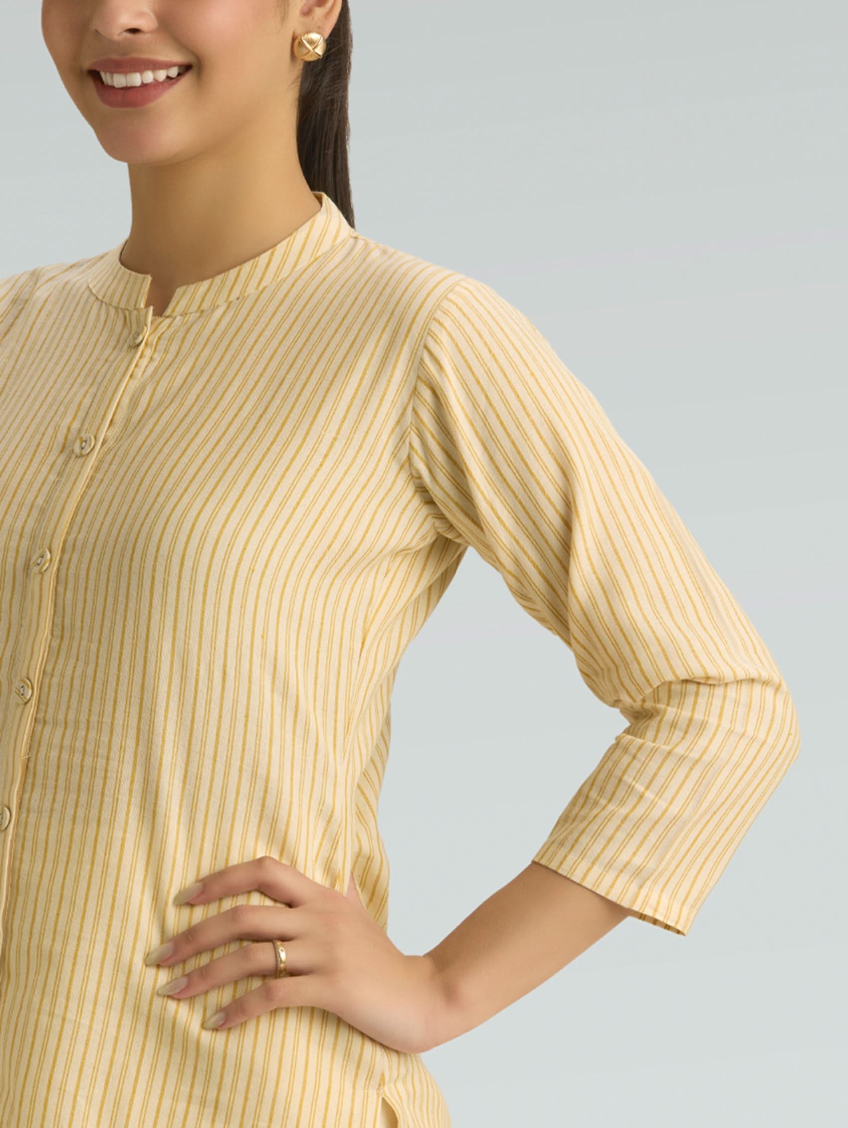 Woman wearing a yellow ribbed long-sleeve top against a gray background