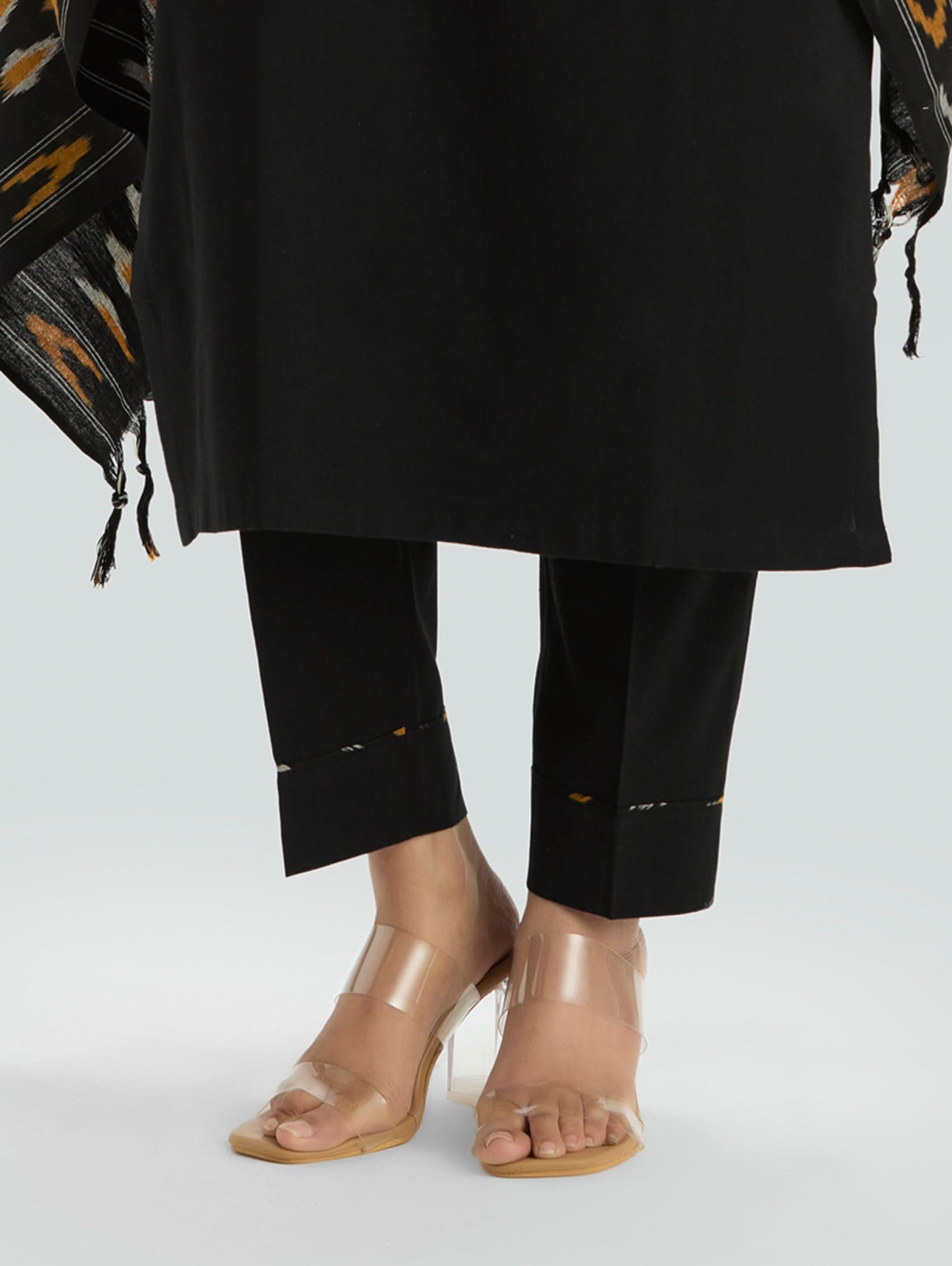 Person wearing black pants and transparent heels on a light gray background