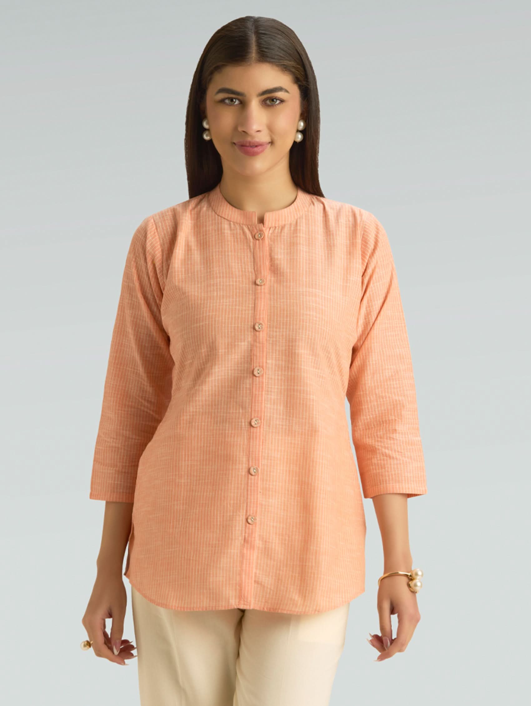 Woman wearing a peach-colored checkered shirt against a gray background
