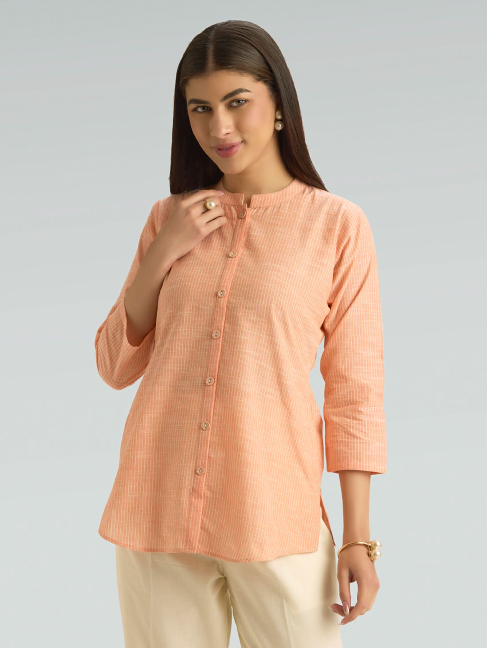 Woman wearing a peach-colored shirt with a plain background