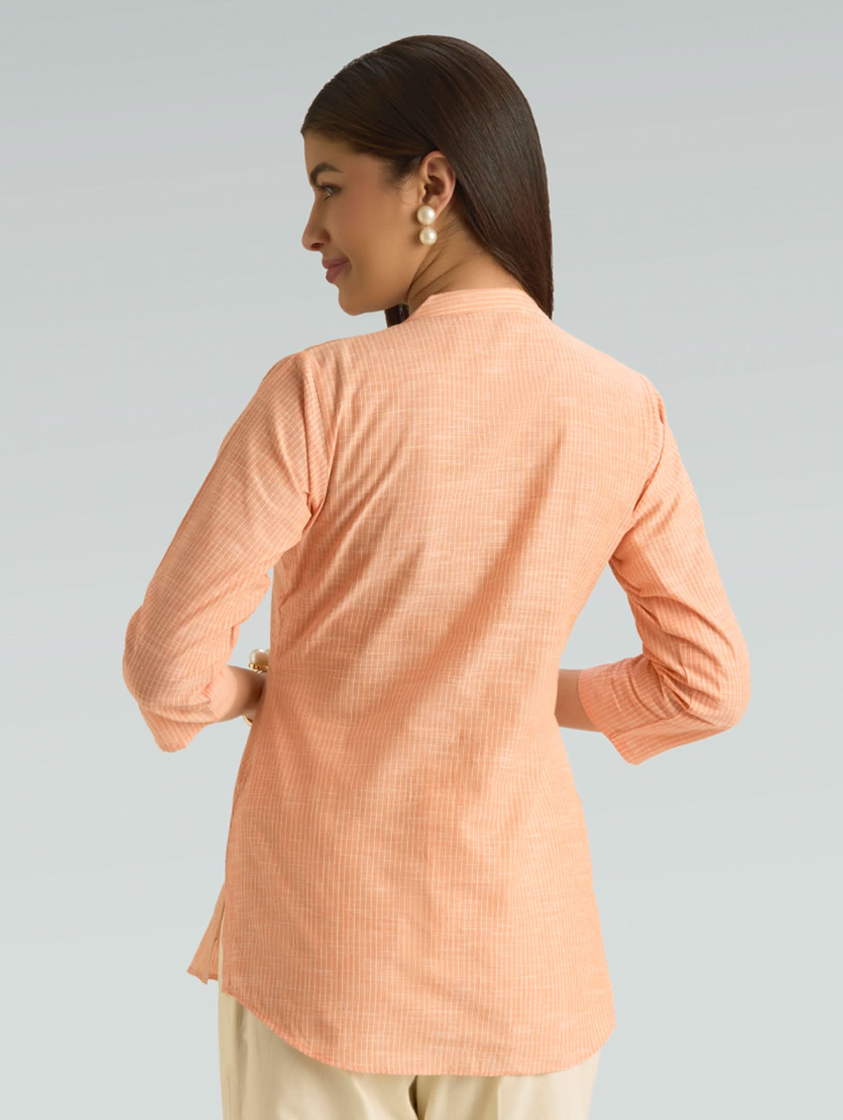 Woman wearing a peach-colored blouse against a gray background