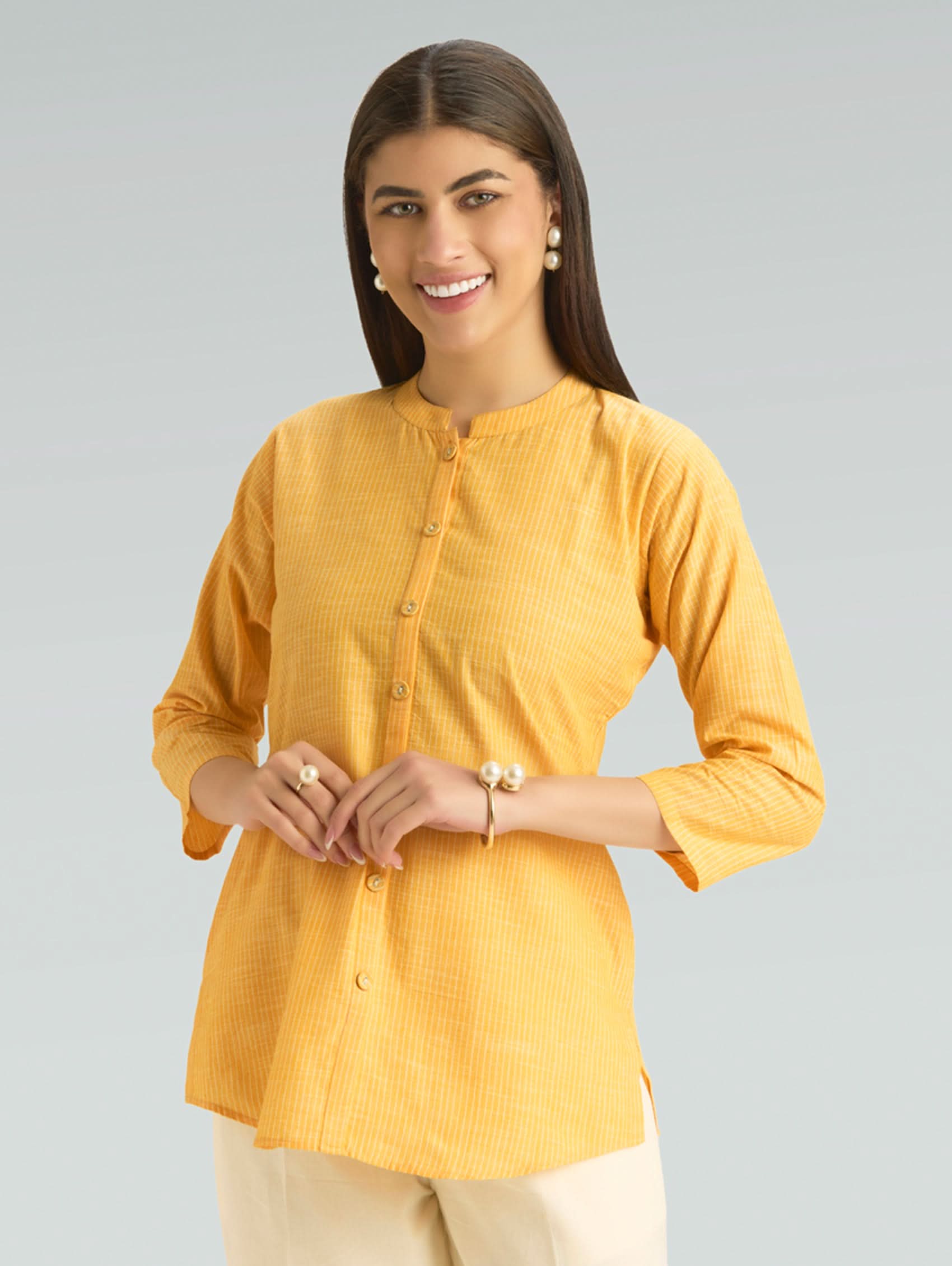 Woman wearing a yellow shirt against a gray background