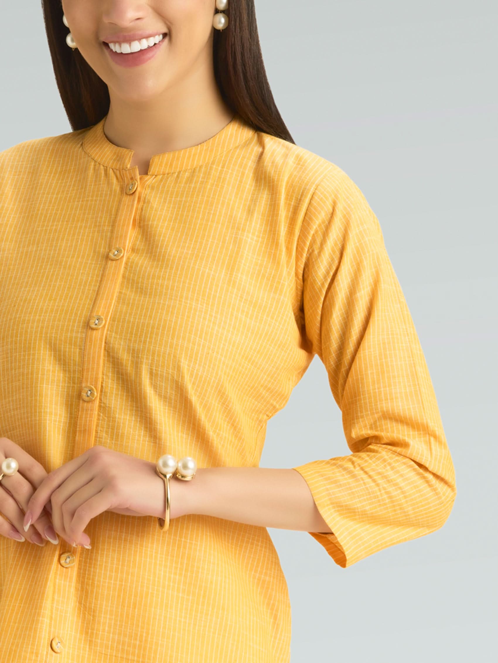 Woman wearing a yellow kurta with a plain background