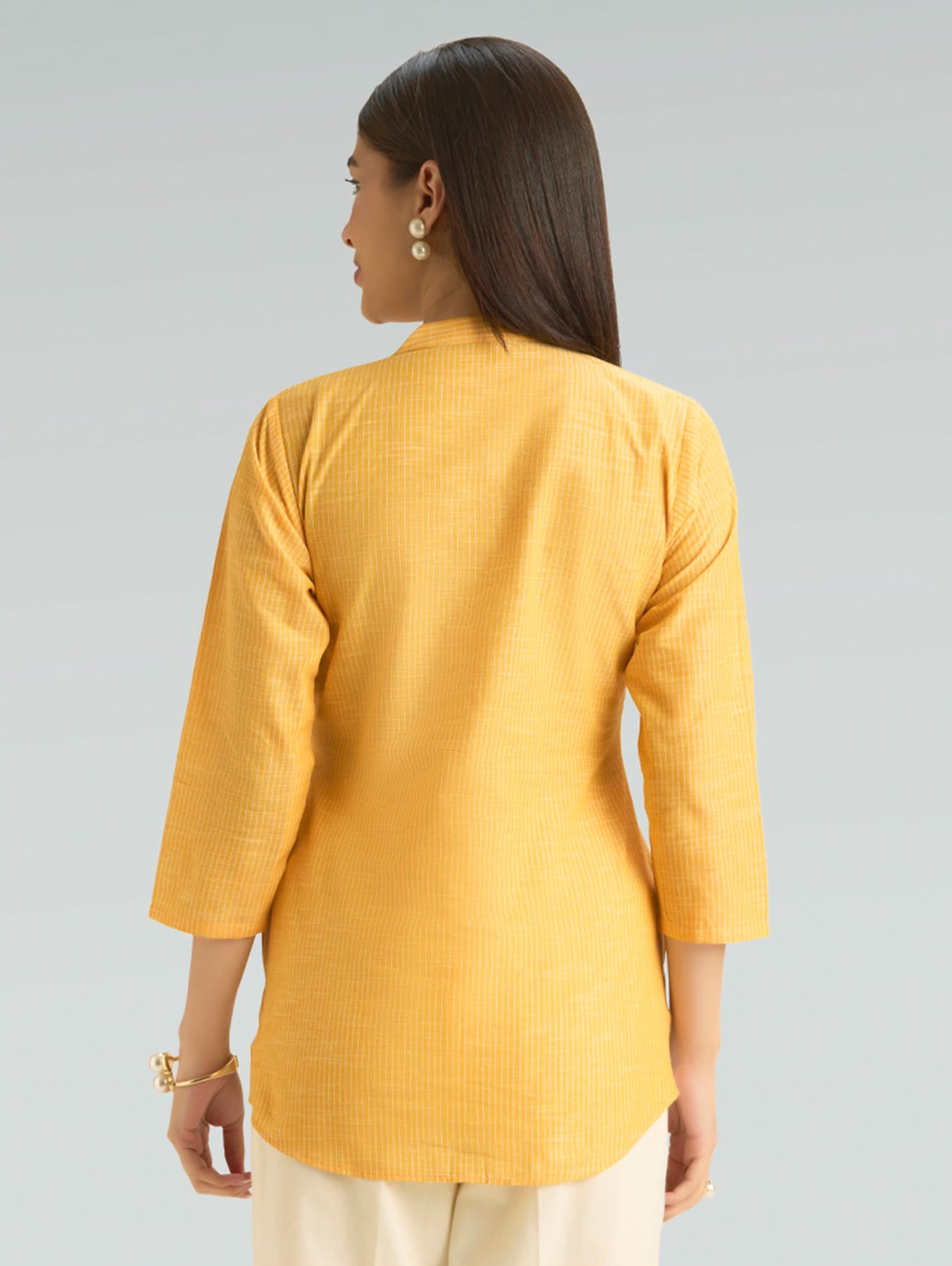 Woman wearing a yellow textured shirt on a gray background