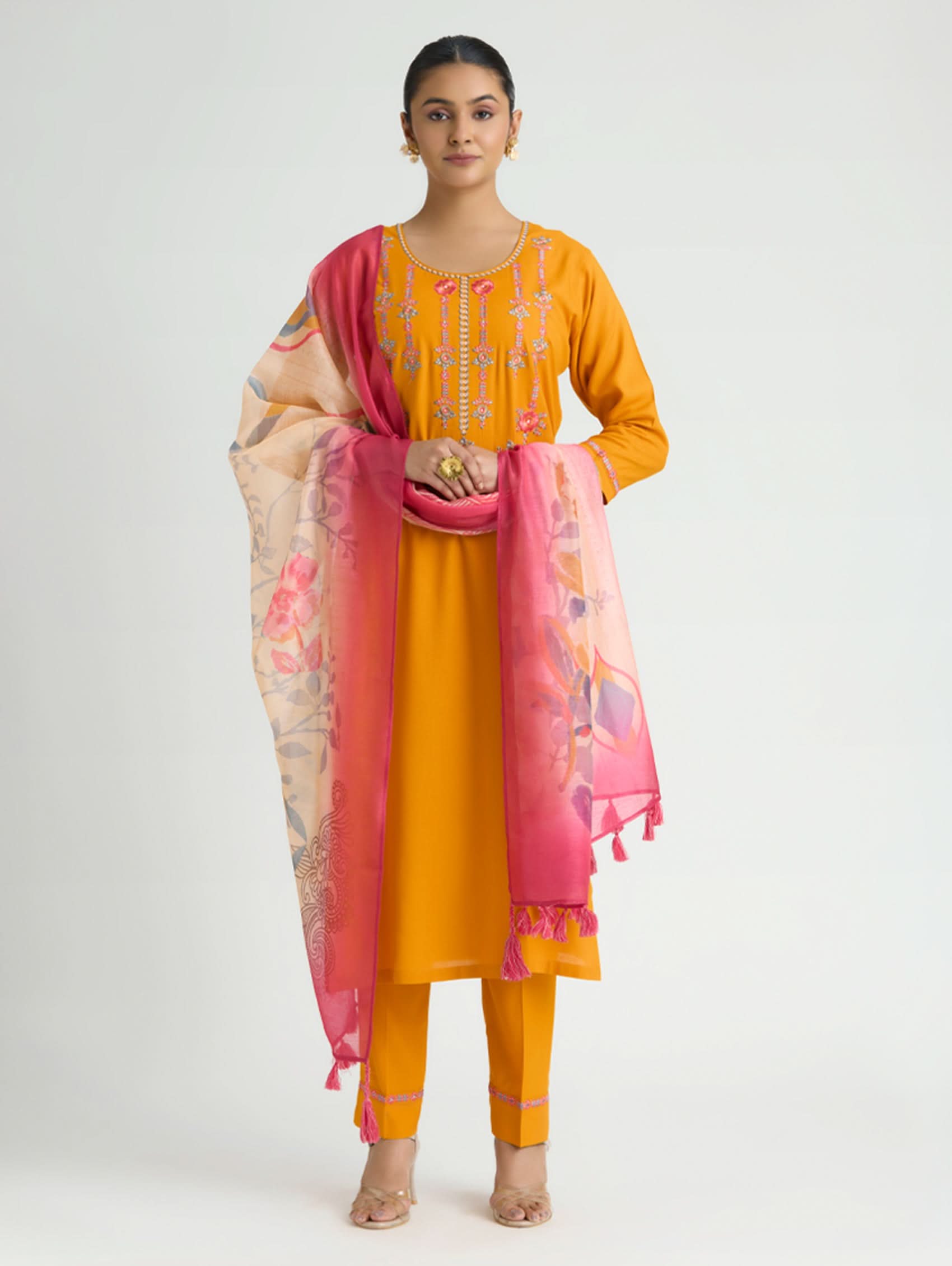 Woman wearing a mustard yellow outfit with a pink dupatta on a white background