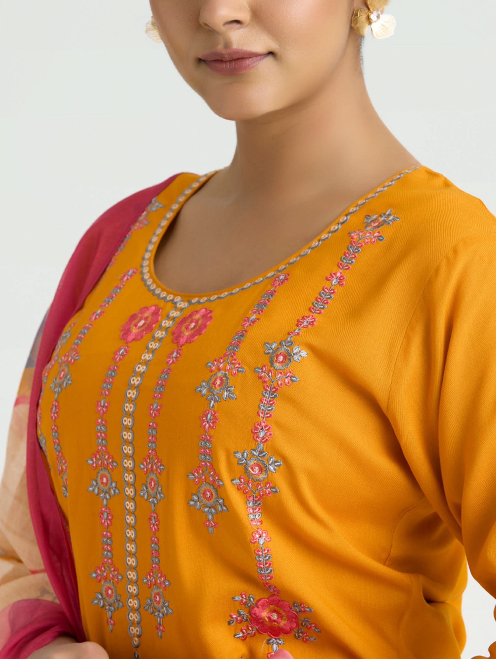 Close-up of a person wearing an orange embroidered top with a pink inner lining.