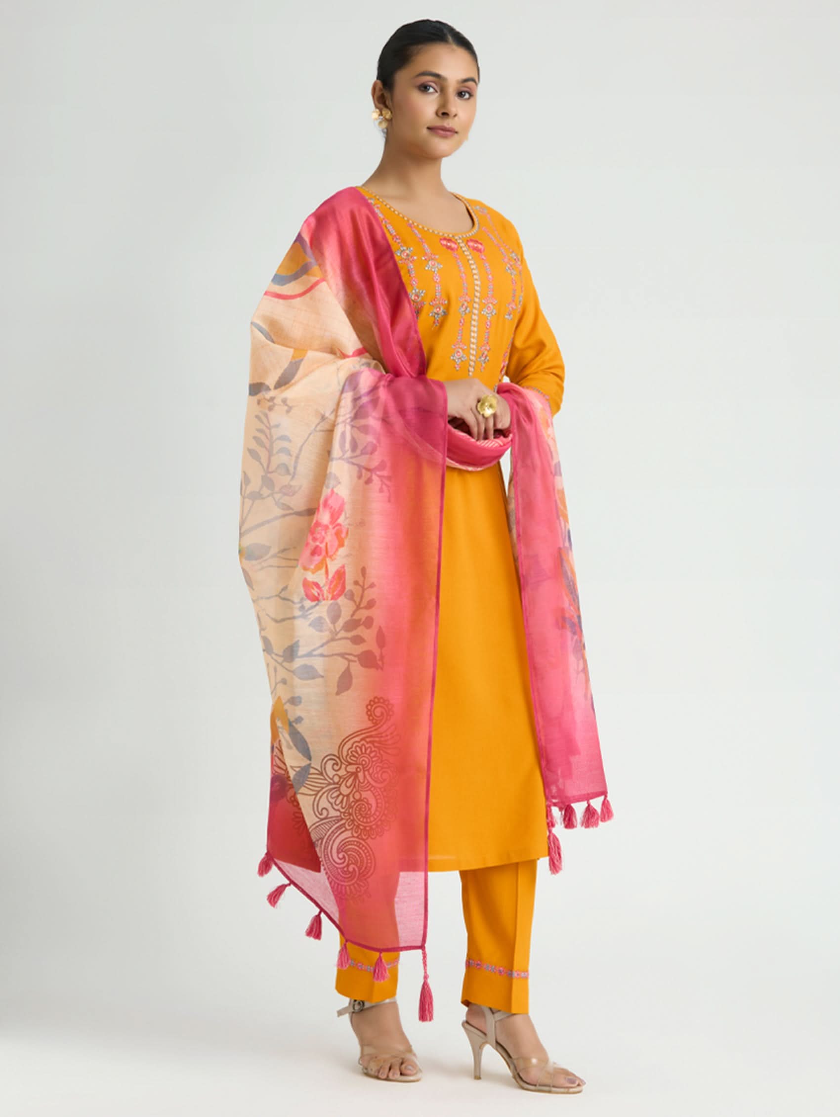 Woman wearing a yellow outfit with a pink and beige dupatta on a white background