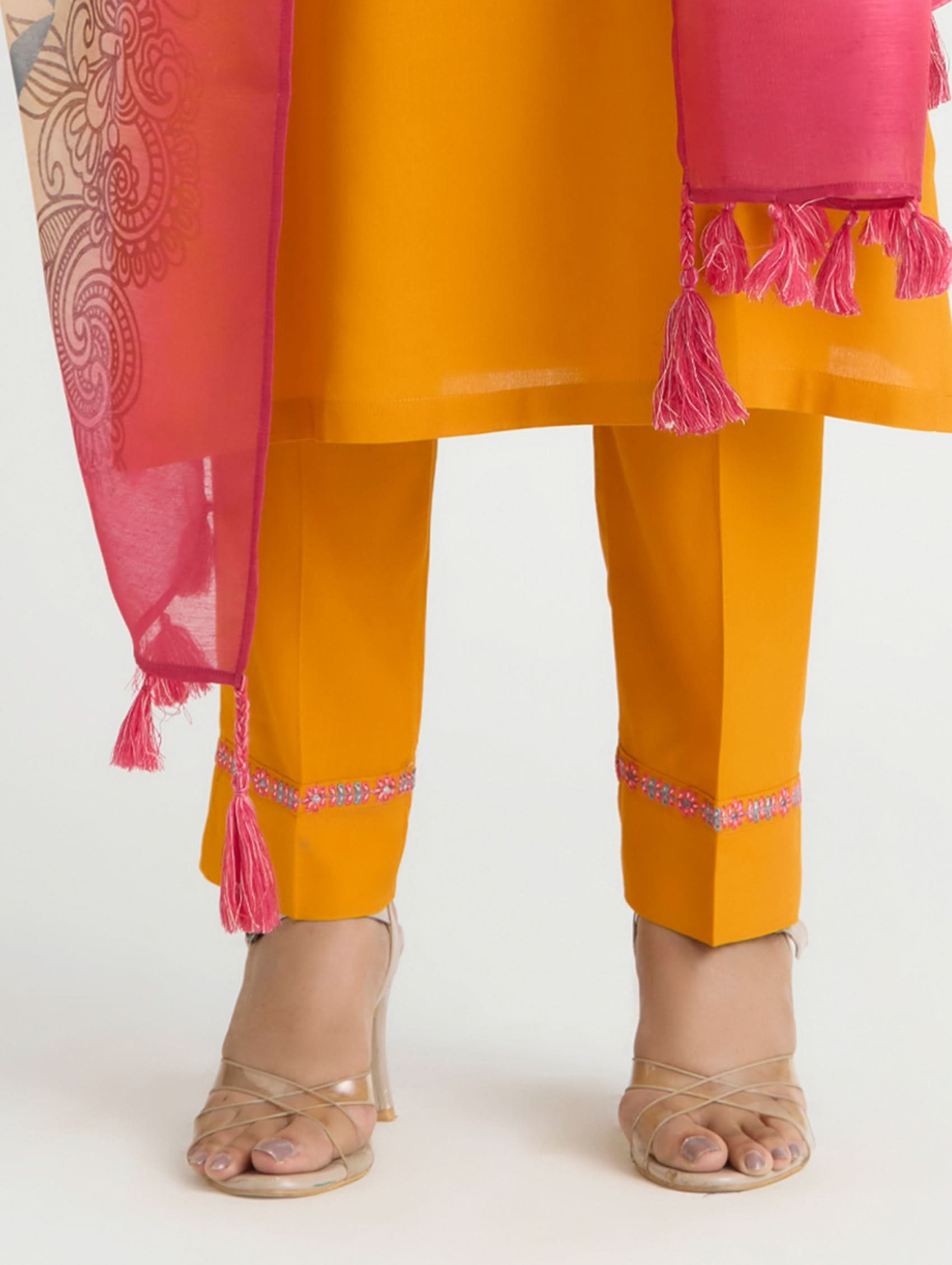 Orange outfit with pink dupatta and tassels on a white background
