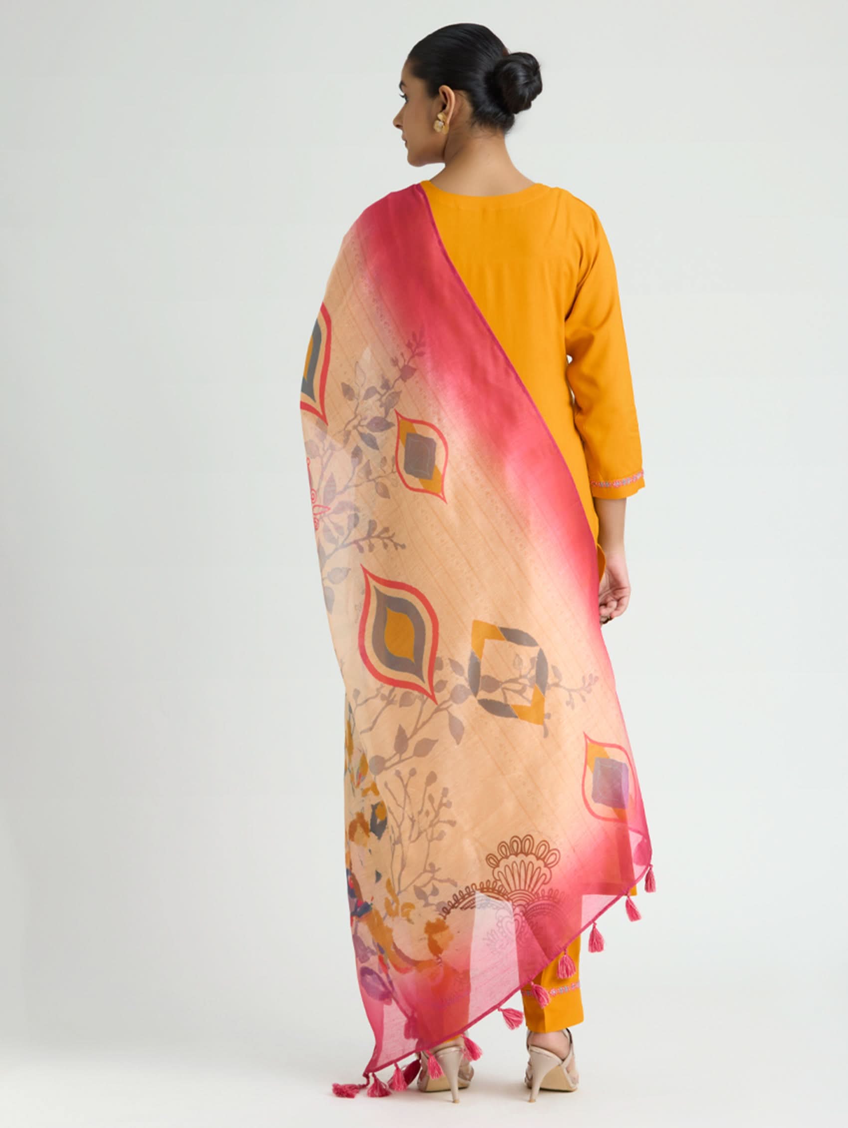Woman wearing a yellow outfit with a patterned pink dupatta on a white background