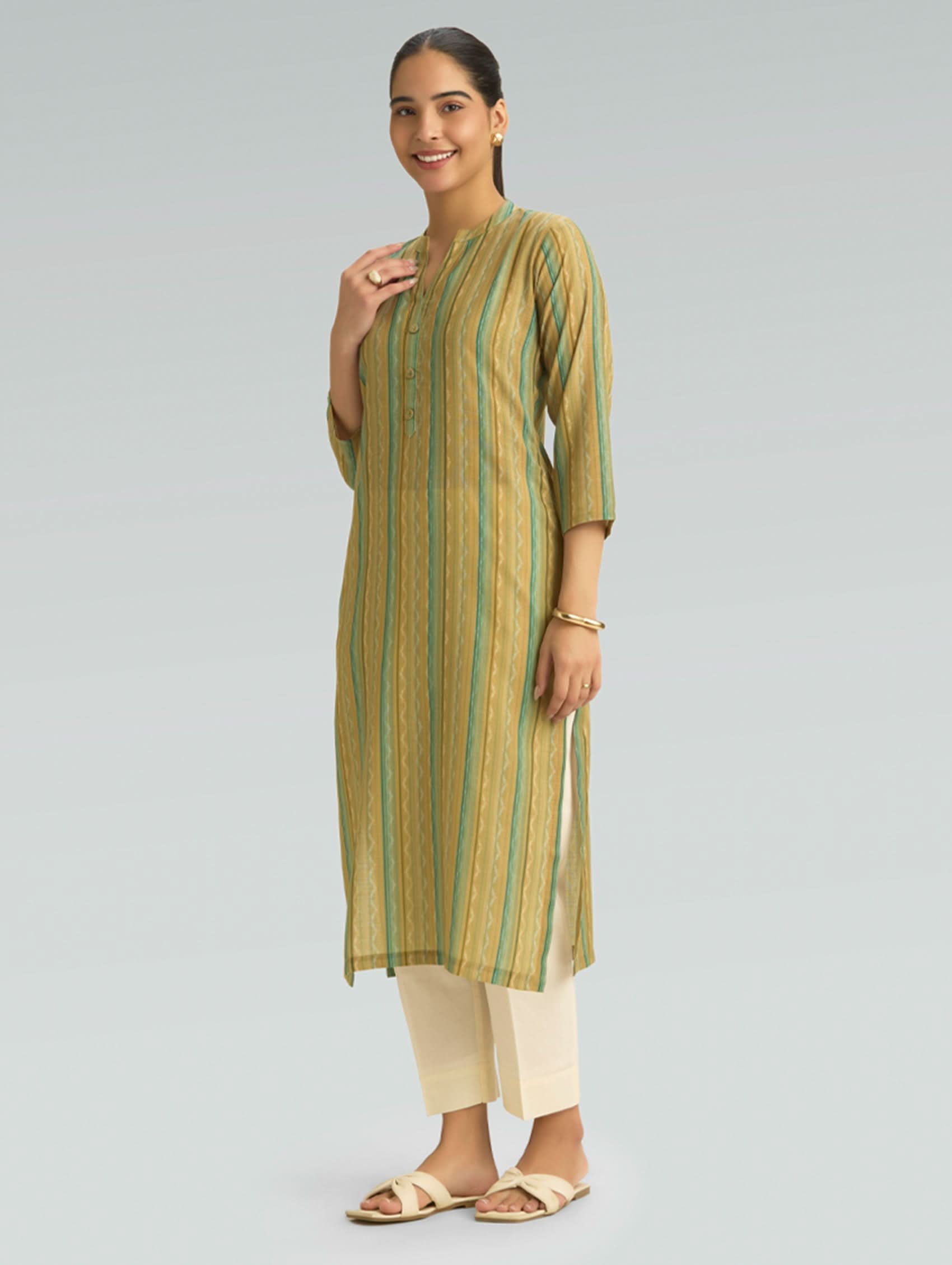 Woman wearing a green and beige striped kurta with white pants on a gray background
