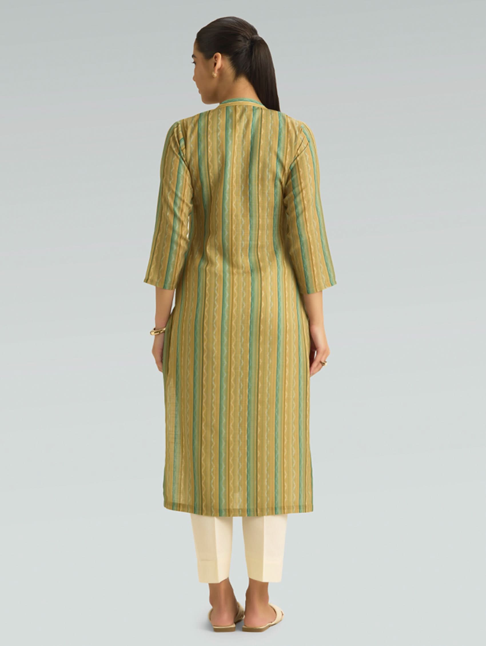 Woman wearing a green and beige striped kurta with white pants on a gray background