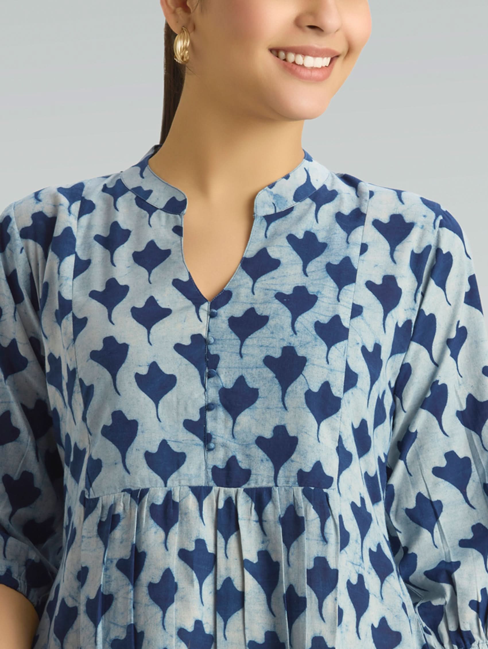 Woman wearing a blue and white patterned dress against a gray background
