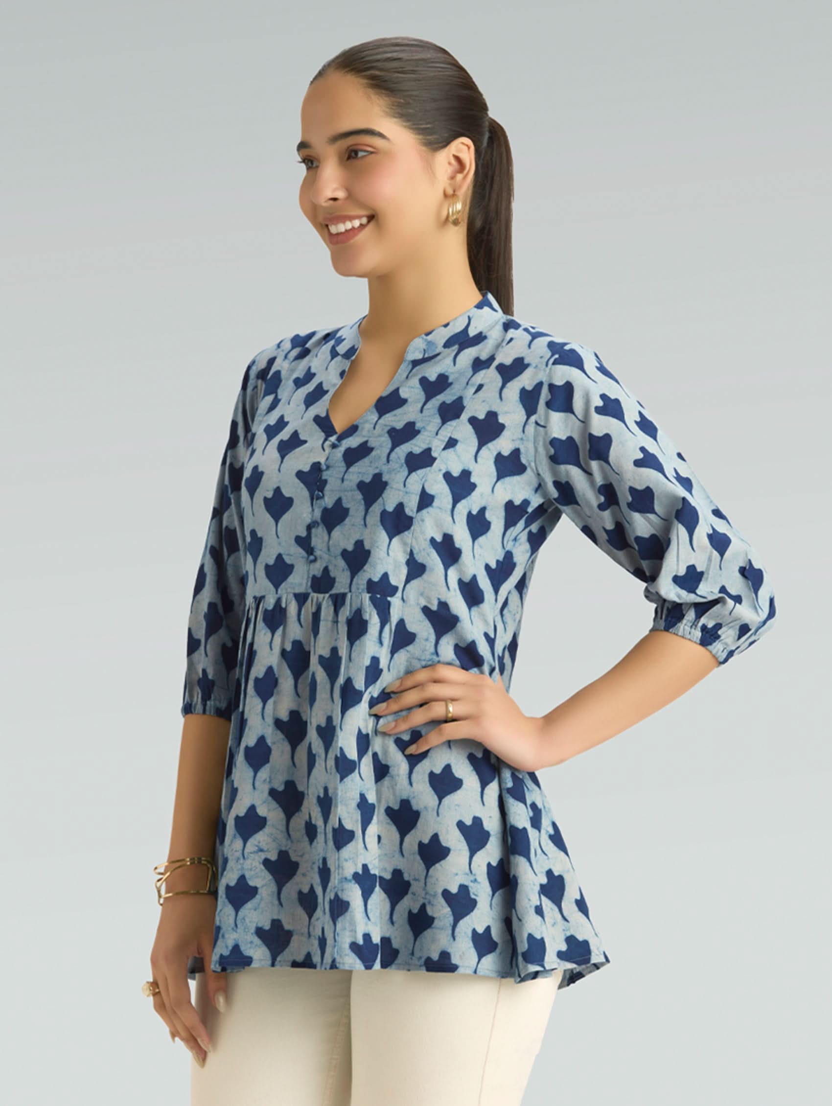 Woman wearing a blue patterned top on a gray background