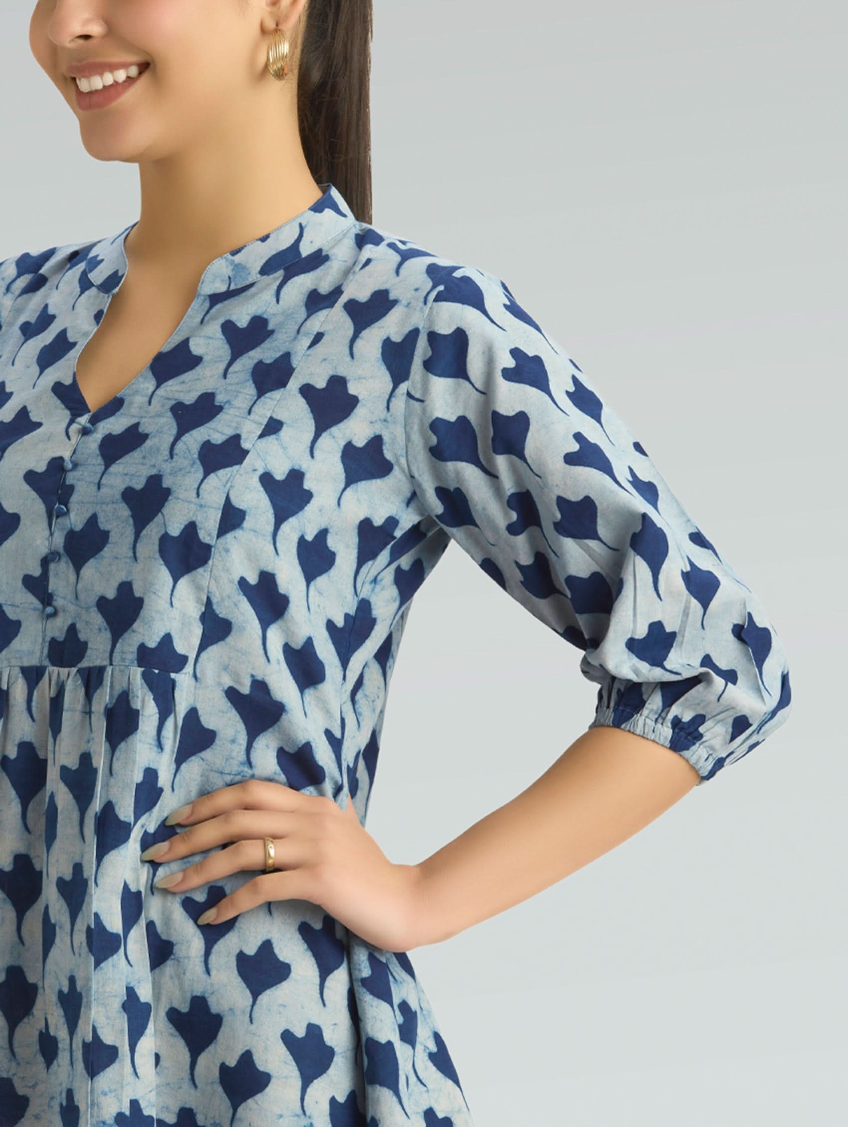 Woman wearing a blue patterned dress on a gray background
