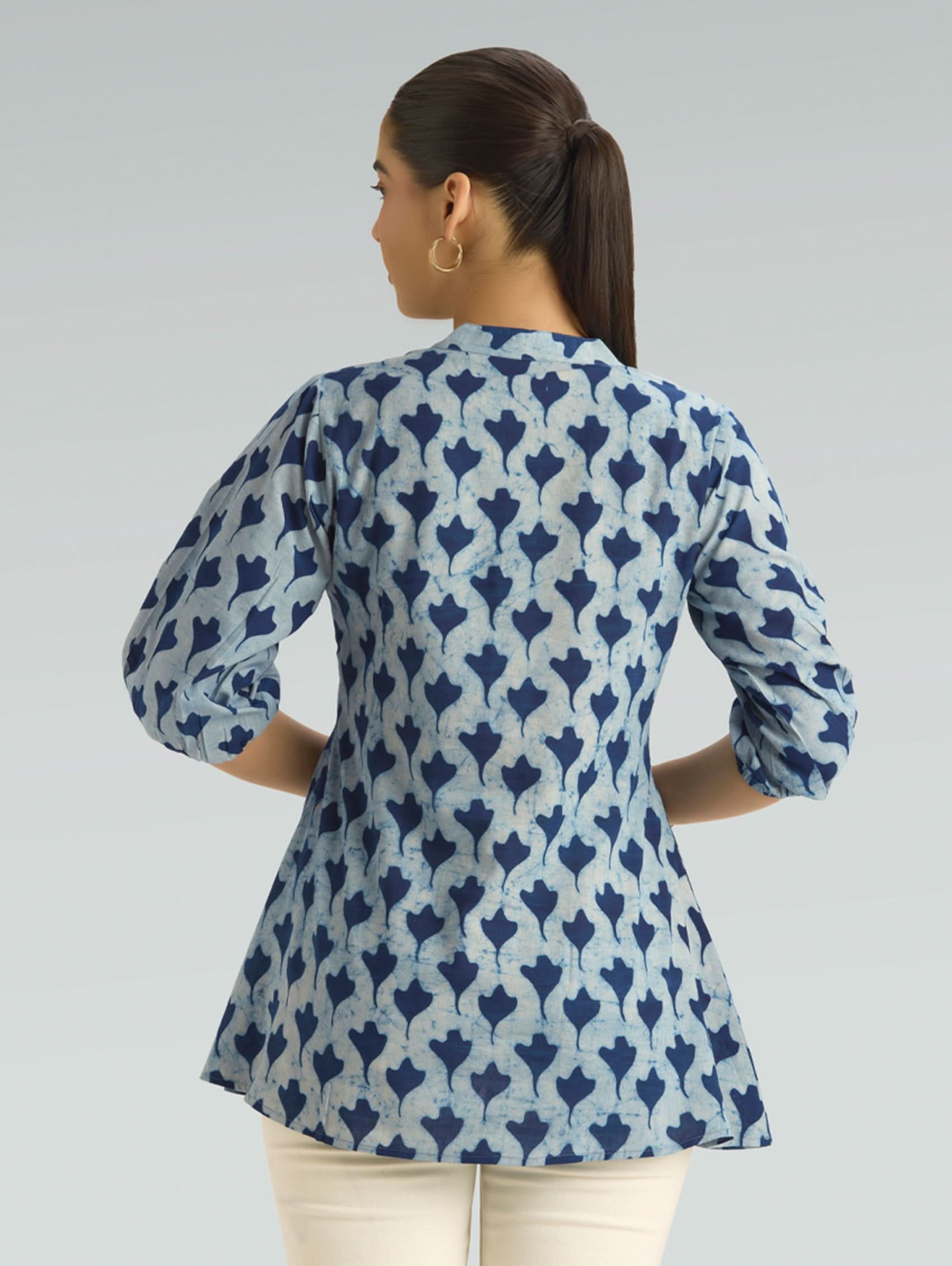 Woman wearing a blue and white patterned shirt against a gray background
