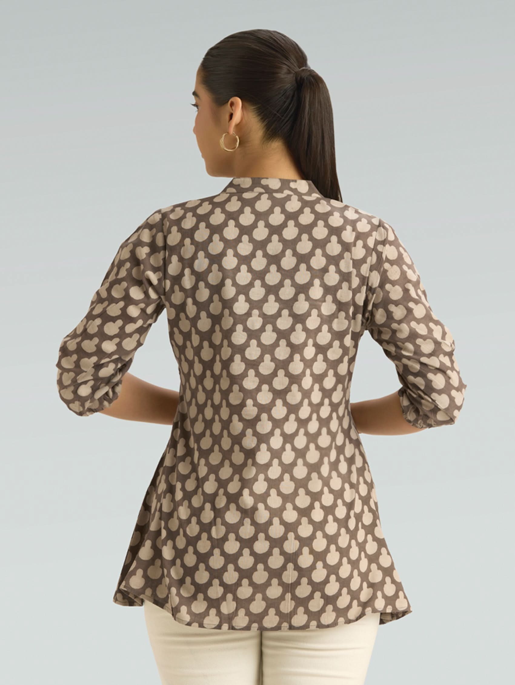 Woman wearing a patterned brown shirt against a gray background