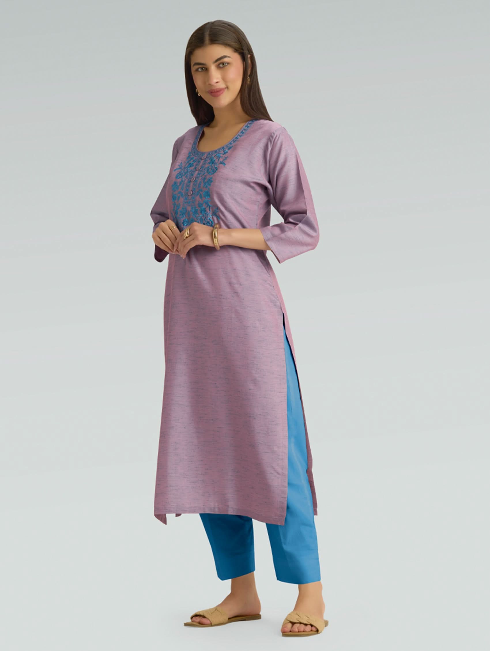 Woman wearing a purple and blue traditional outfit on a gray background