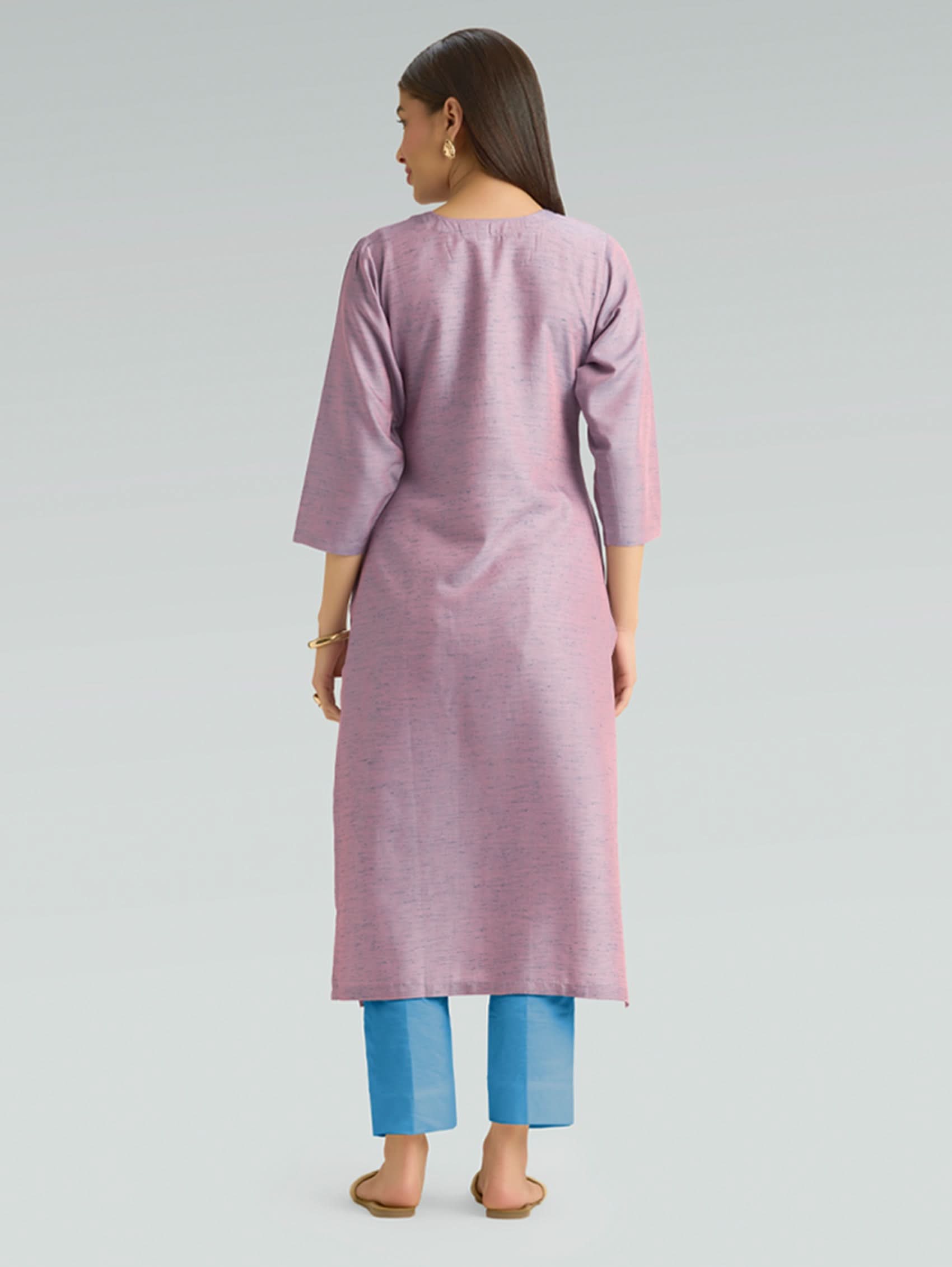 Woman wearing a pink kurta with blue pants on a gray background