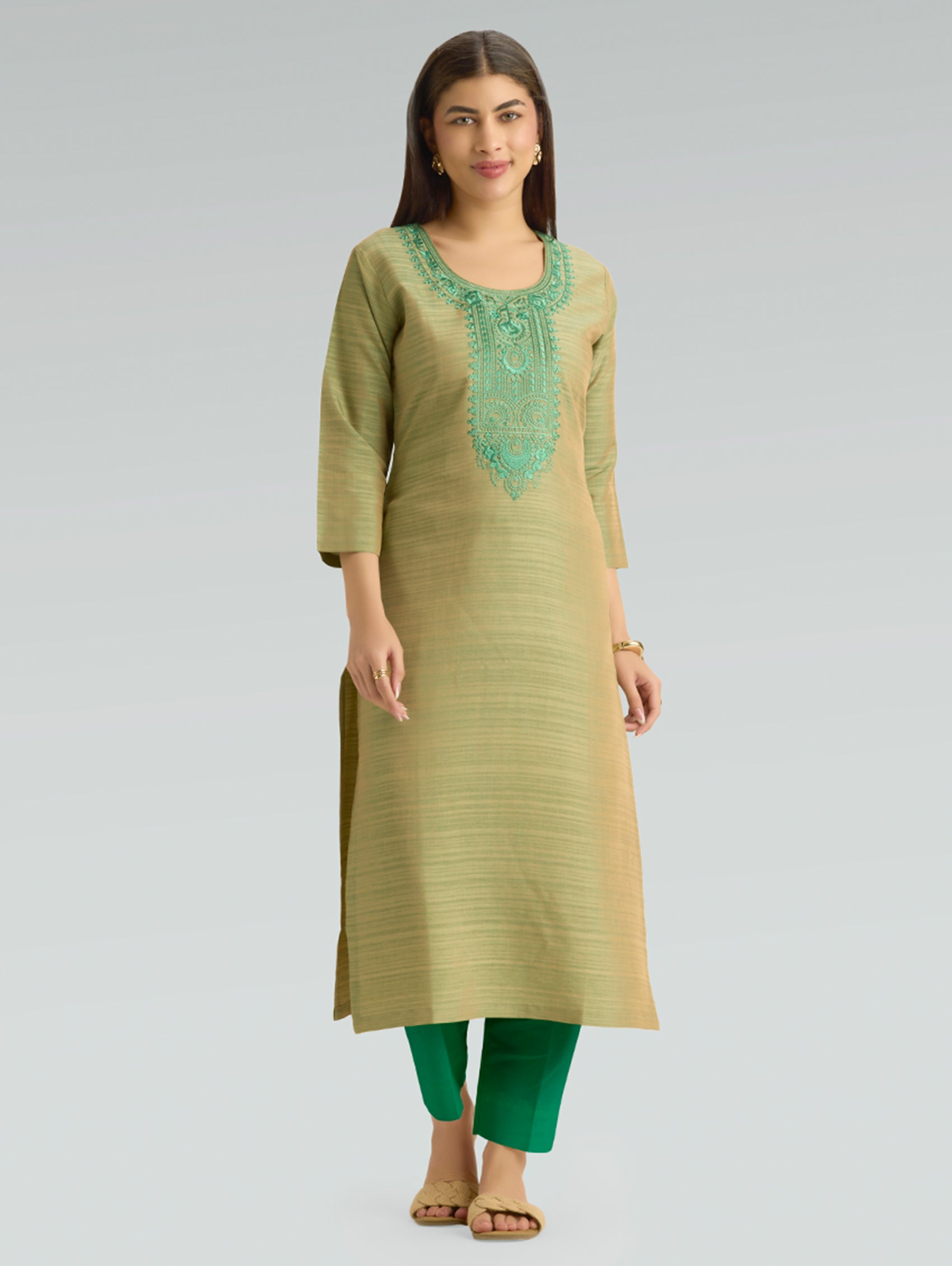 Woman wearing a green kurta with embroidery on a gray background