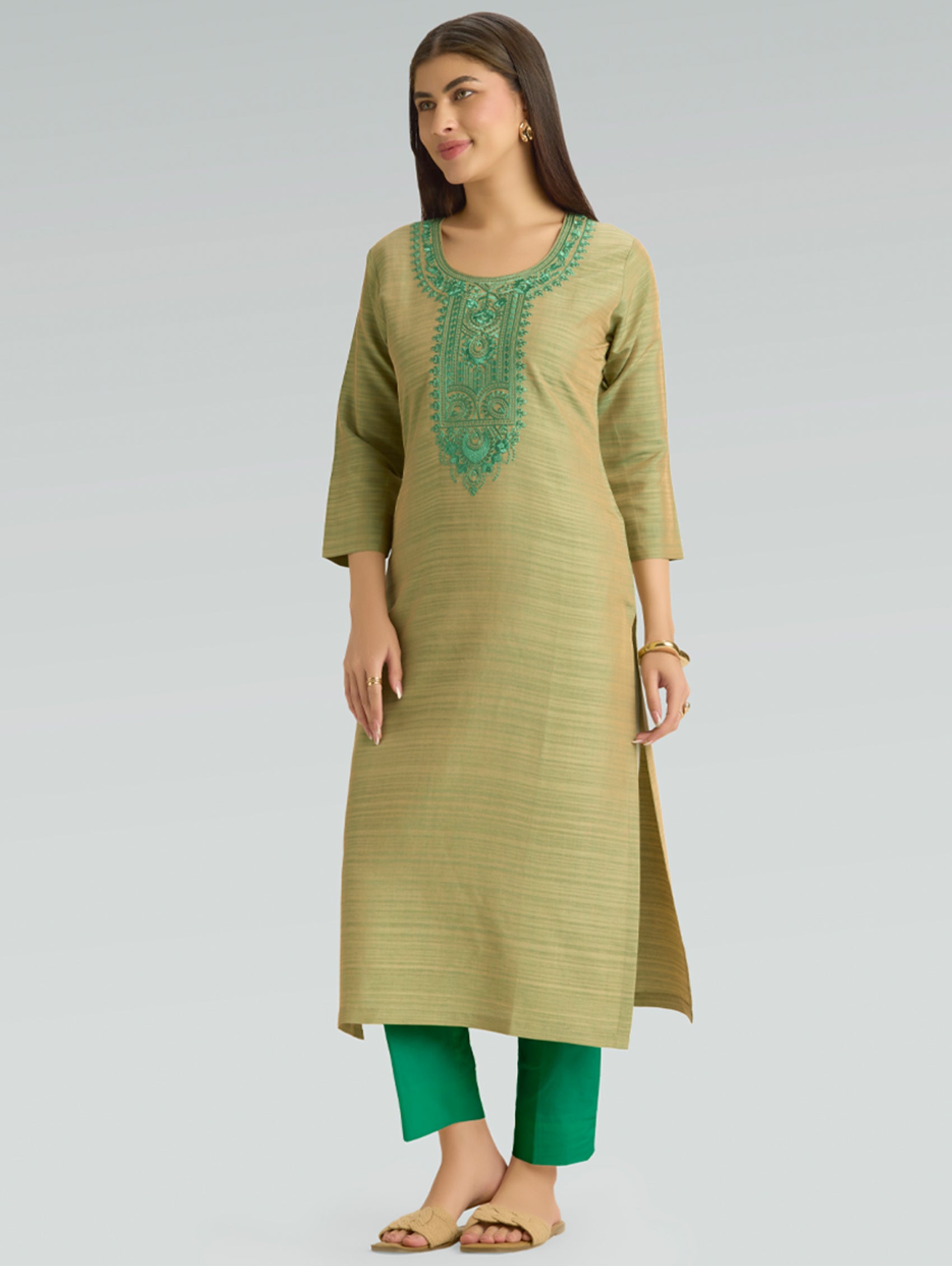 Woman wearing a green kurta with embroidery on a gray background