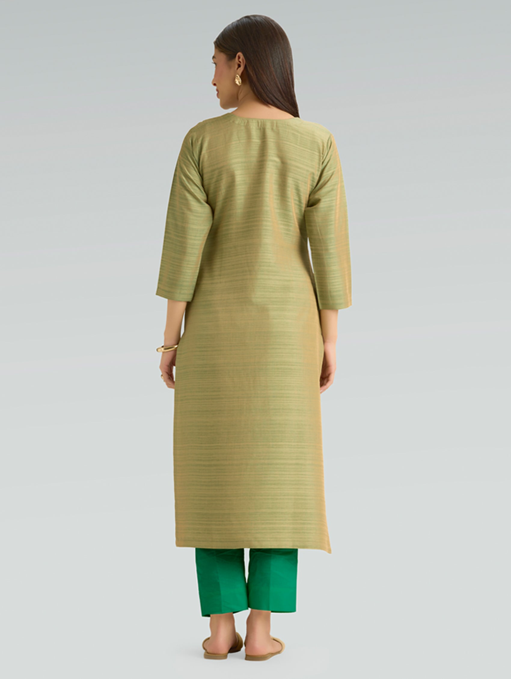 Woman wearing a green kurta with green pants on a light gray background