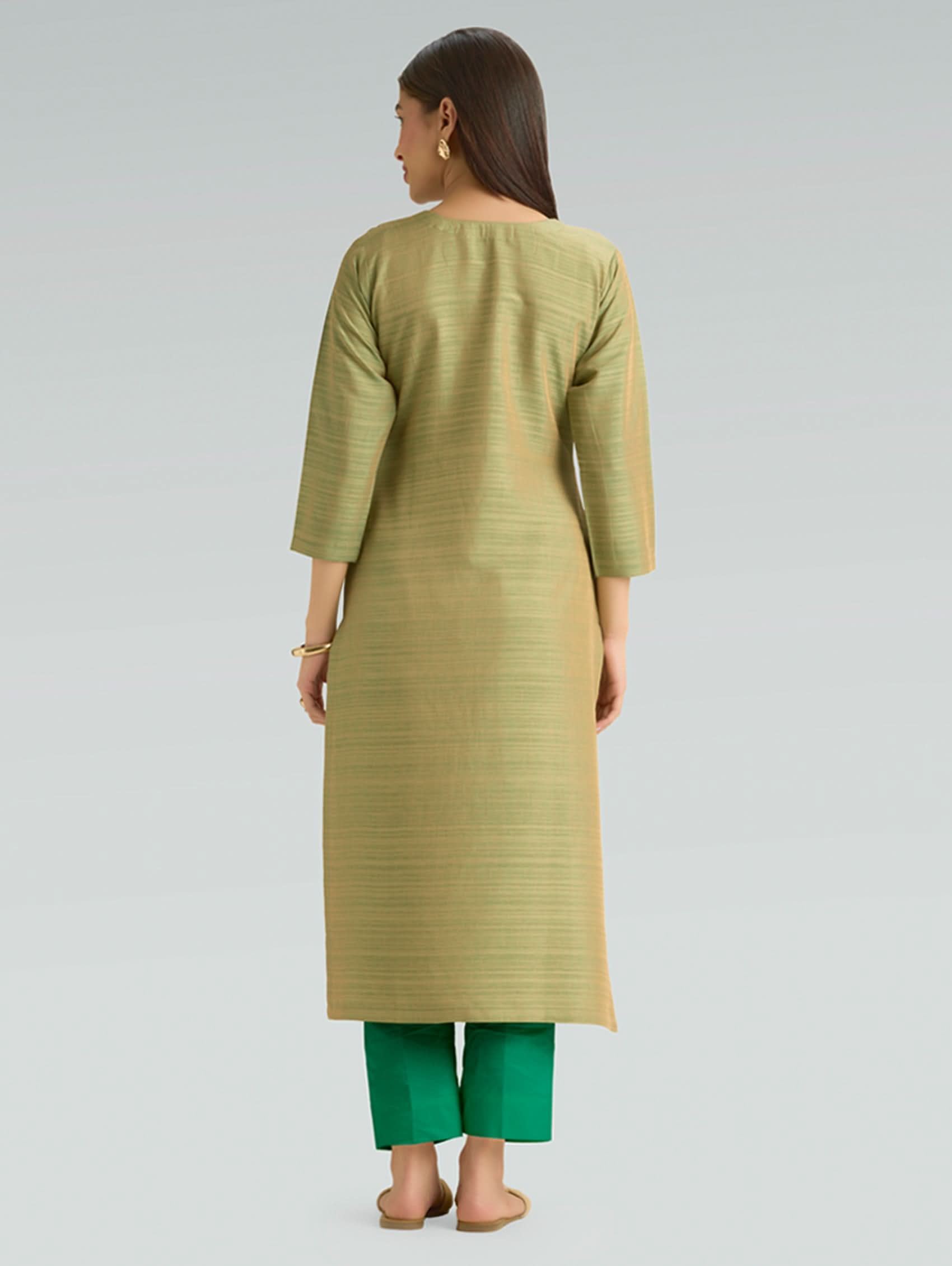 Woman wearing a green kurta with green pants on a light gray background