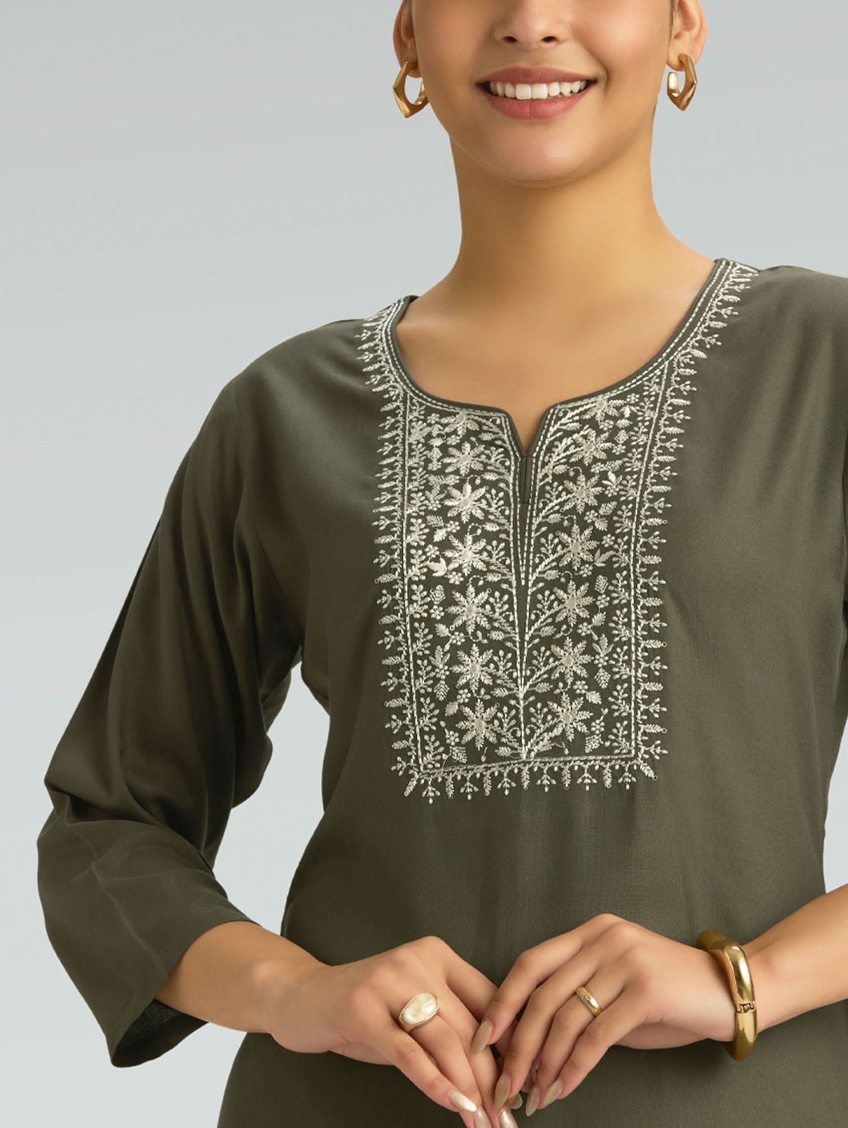 Woman wearing a green kurta with white embroidery on a gray background