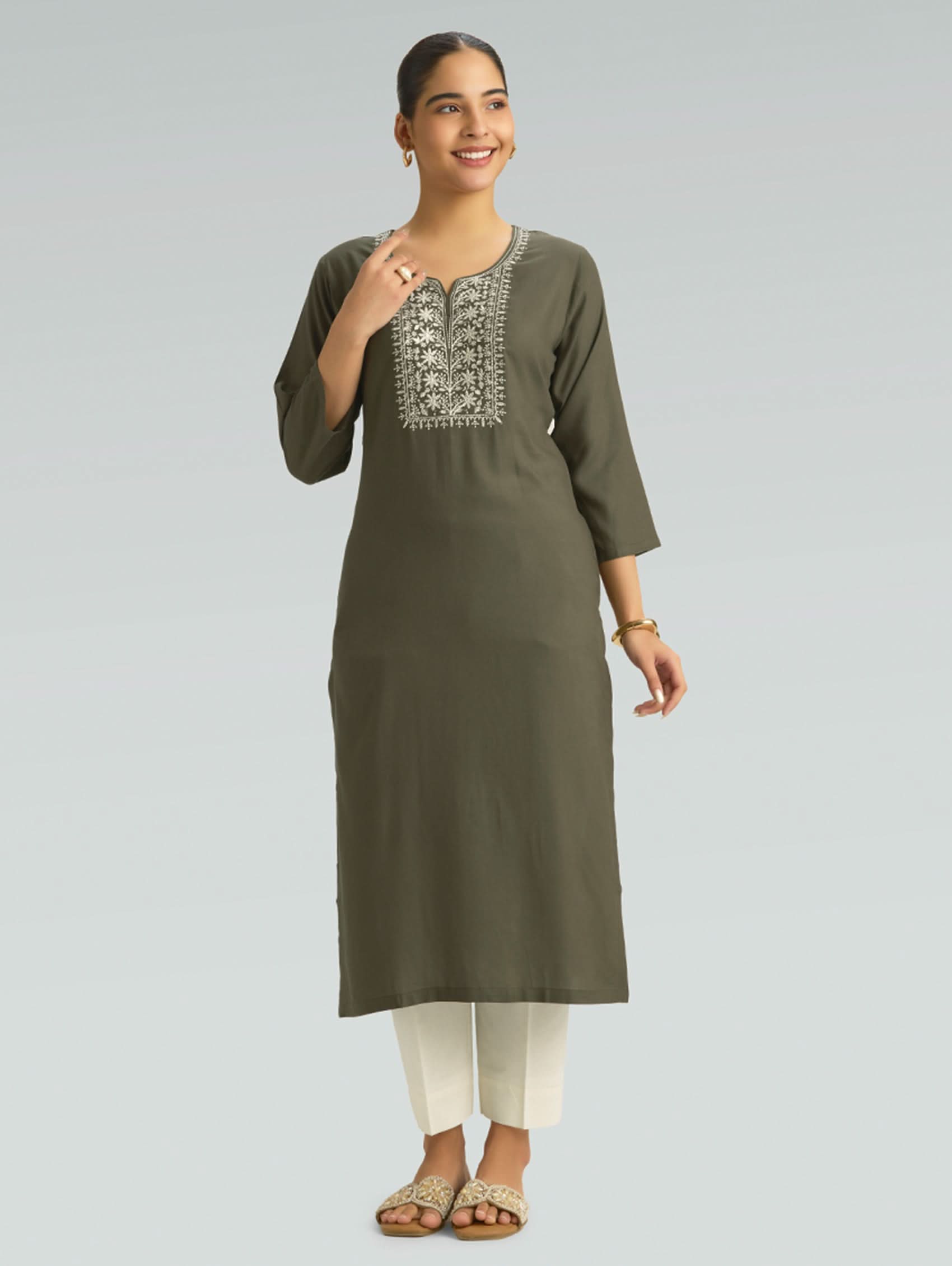 Woman wearing an olive green kurta with white embroidery on a light gray background