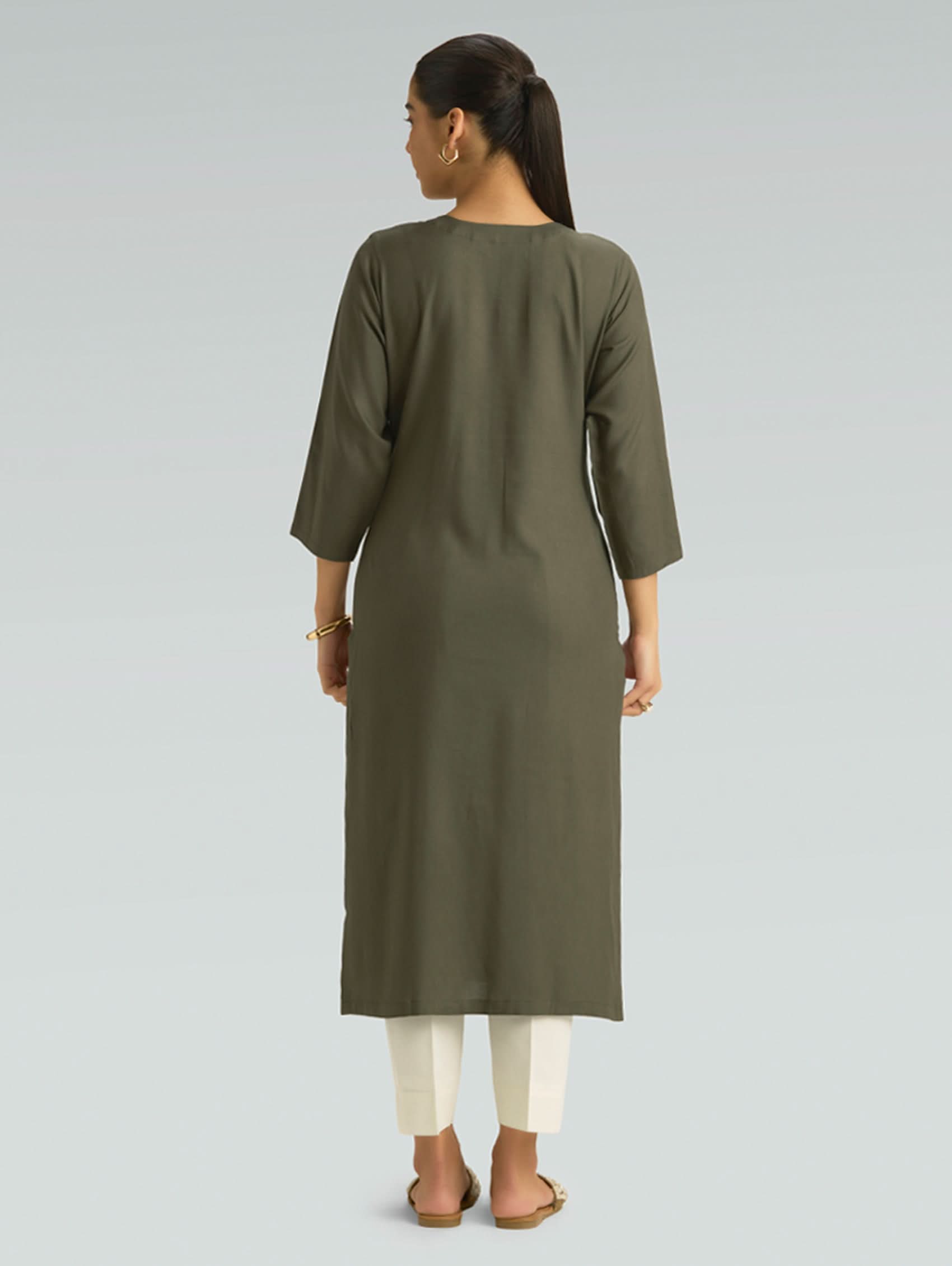 Woman wearing an olive green kurta with white pants on a light gray background